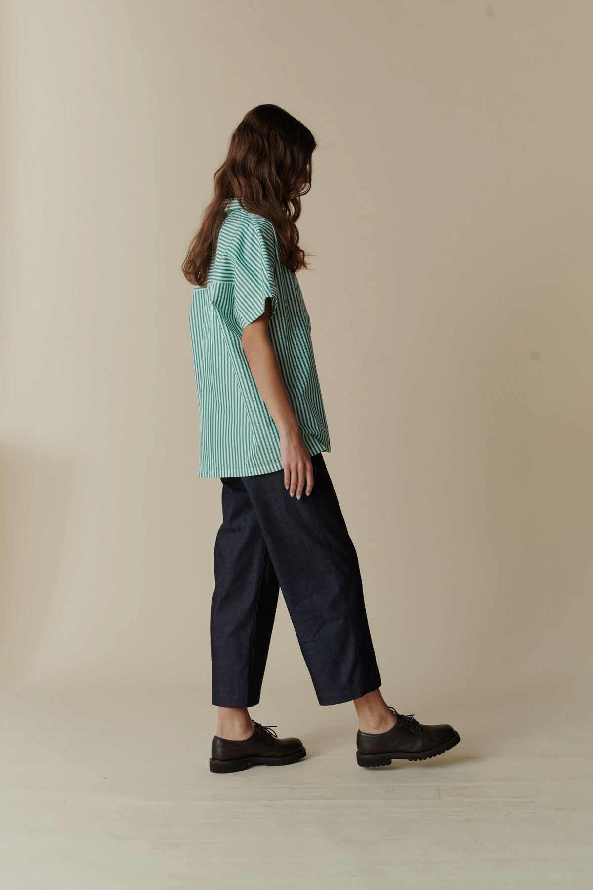 woman wearing oversized green and white short sleeved shirt with cropped wide leg trousers and black shoes