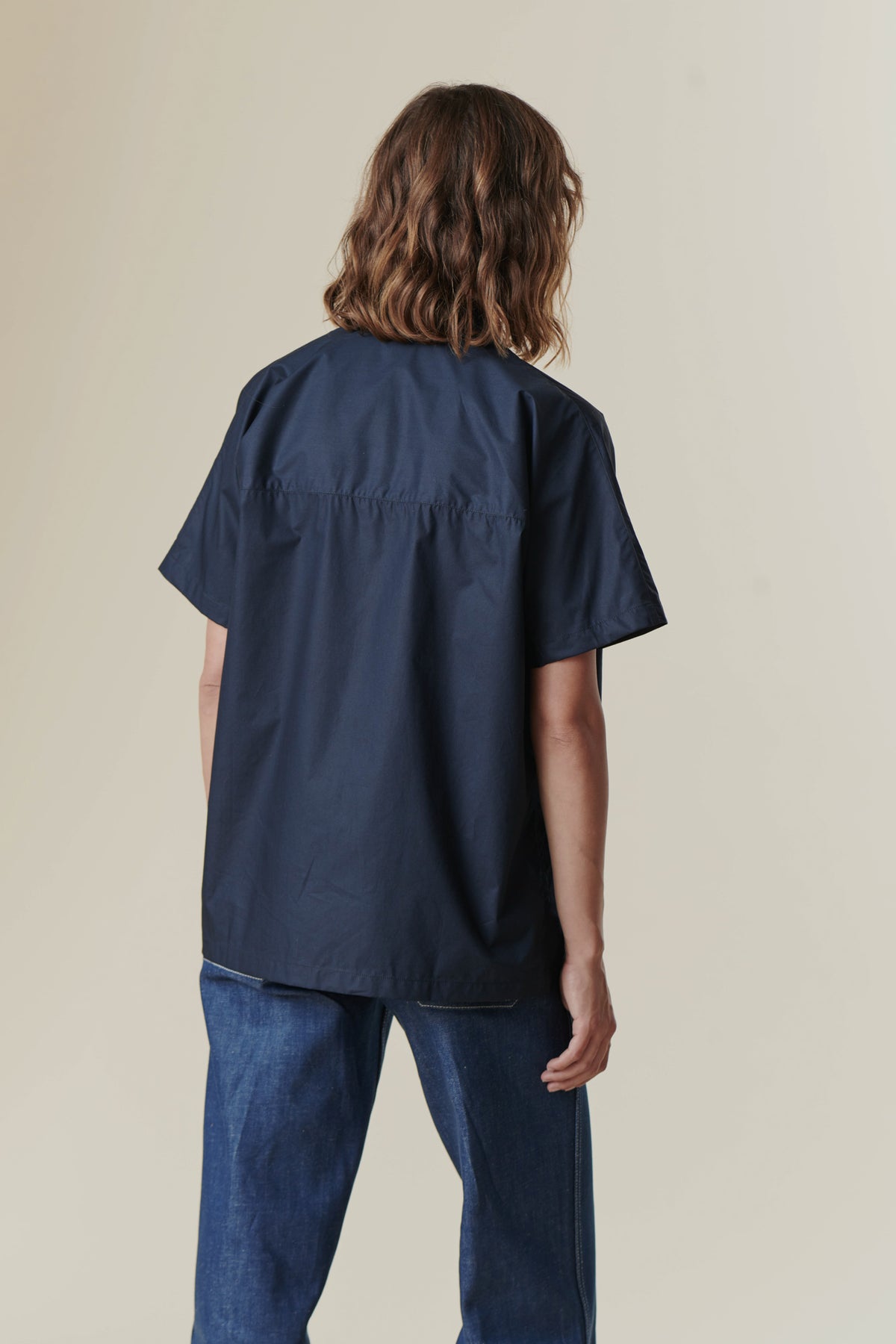 backwards angle photo of woman wearing the short sleeve Ava shirt in Navy.