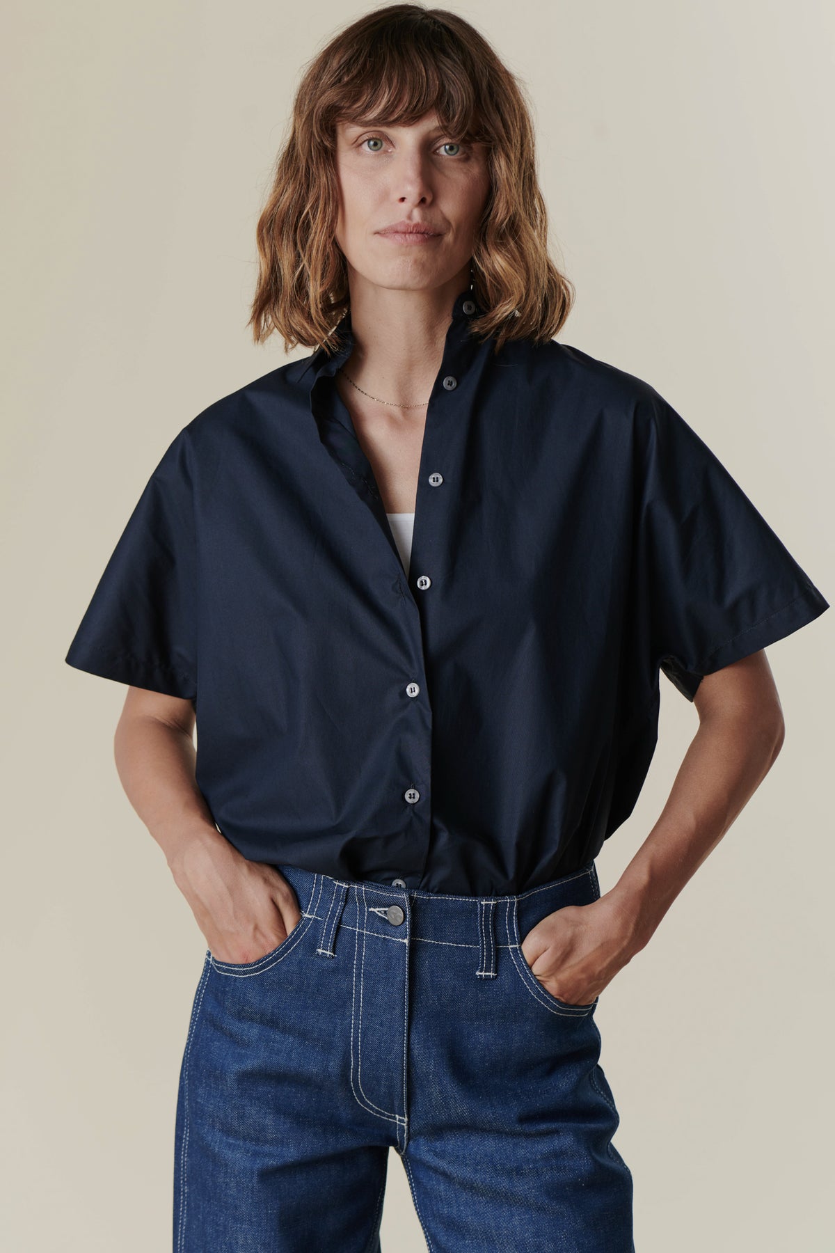 Woman with hands in jean pockets wearing the Ava short sleeve shirt in Navy