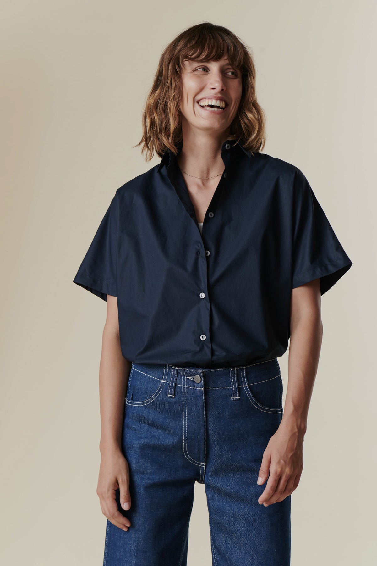 Female wearing front buttoned tucked in navy Ava short sleeve shirt
