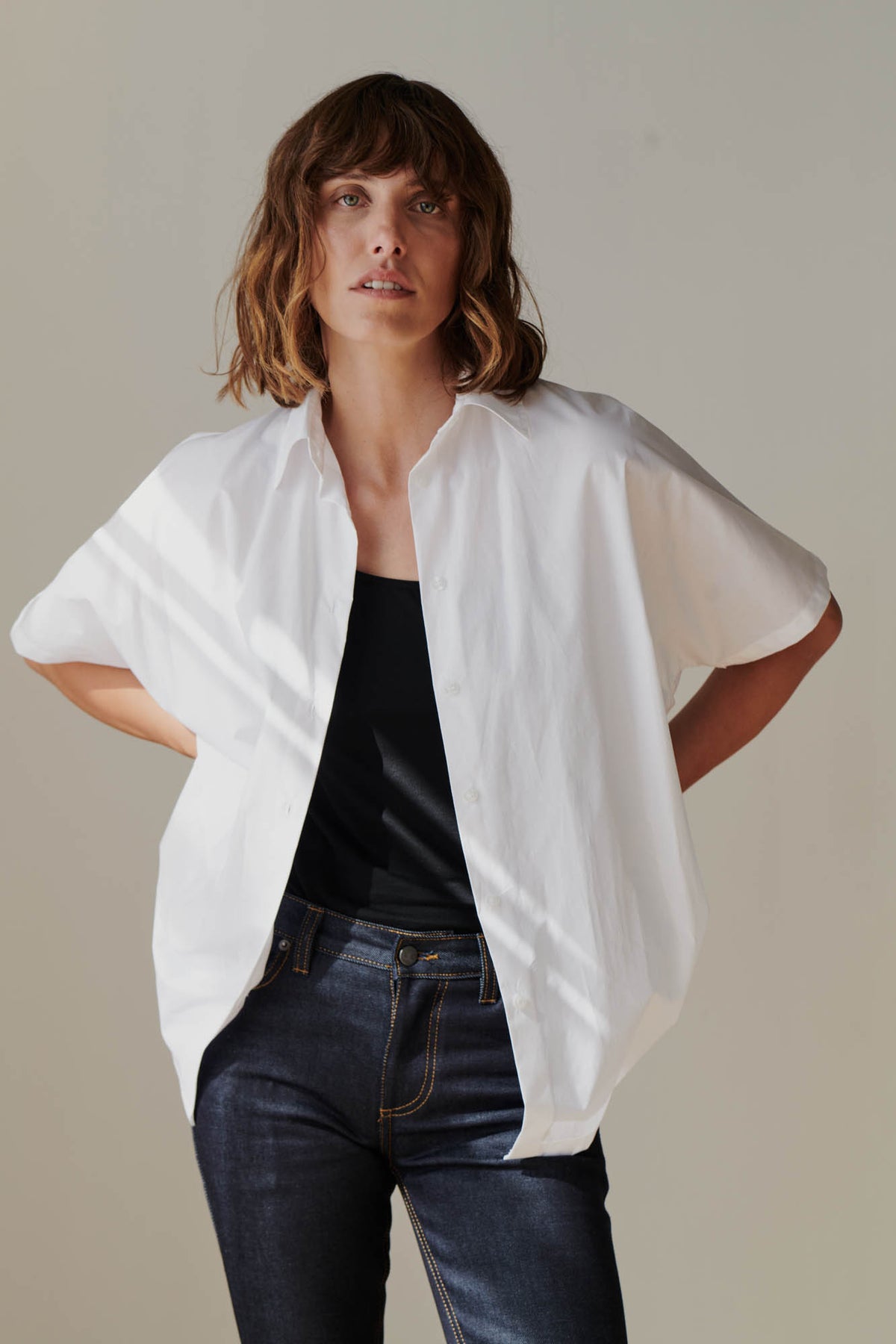 Female wearing Ava short sleeve shirt in white unbuttoned over black camisole 