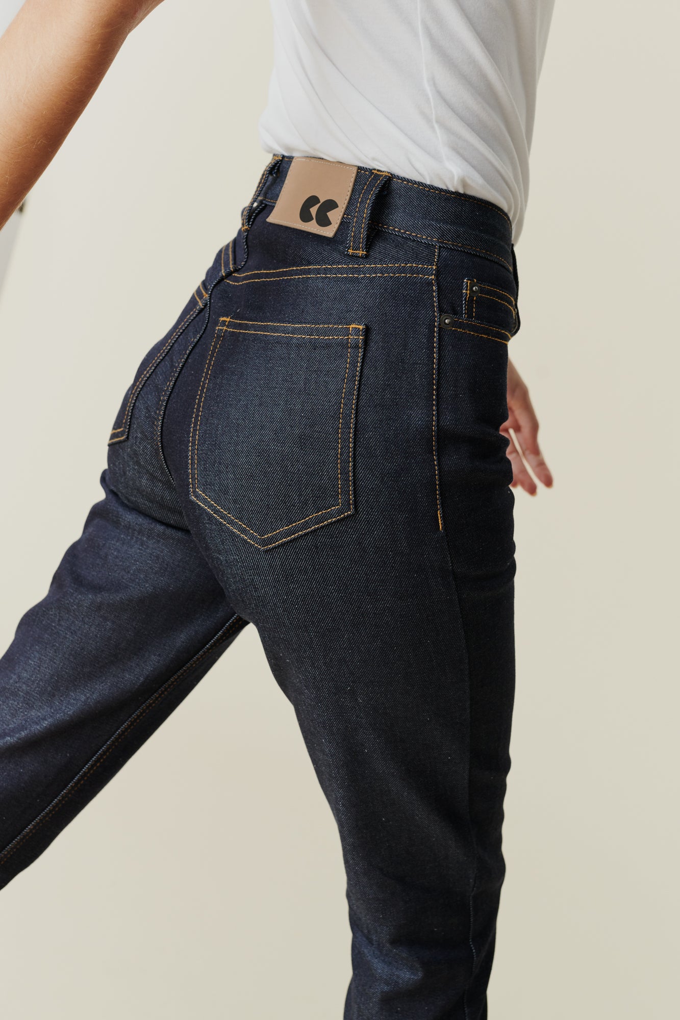 Back pocket and belt loop detail of female wearing straight leg high rise jeans in indigo