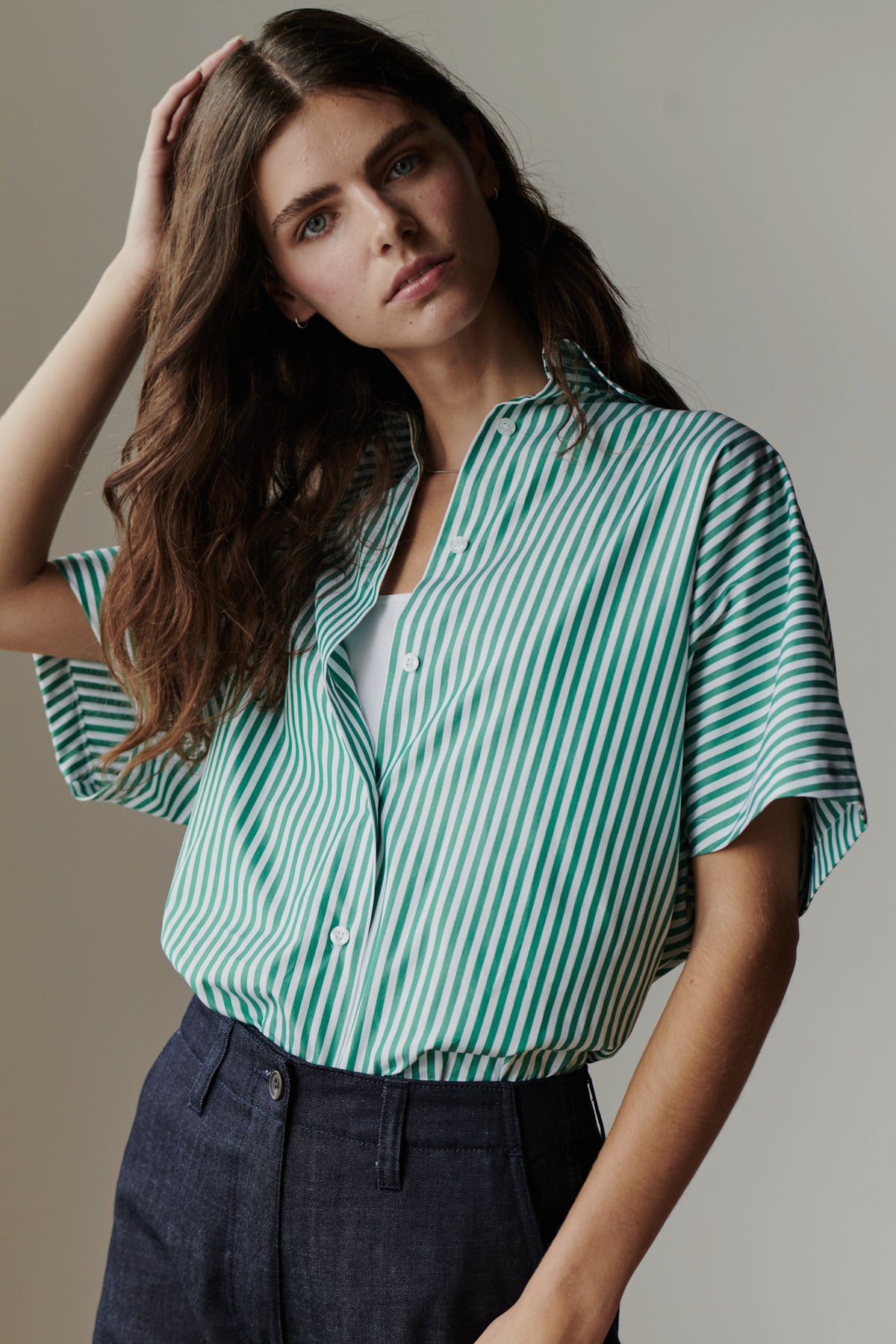 woman wearing green and white striped shirt with hand on her head