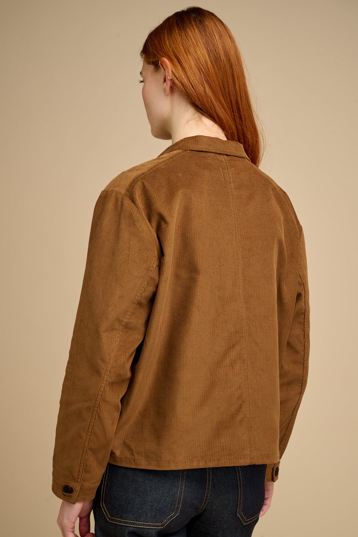 Woman wearing tan coloured cord overshirt against beige background.