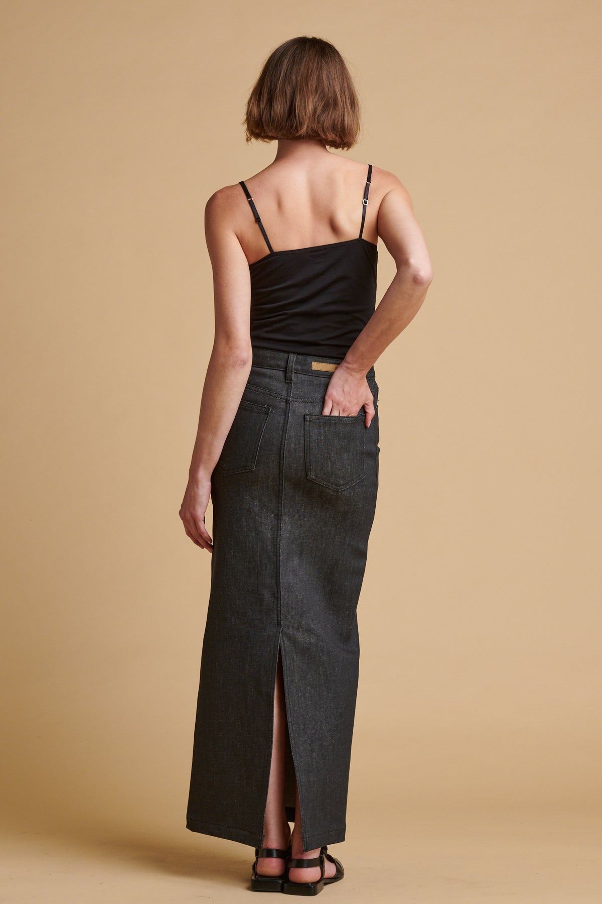 The back of female wearing Frankie denim maxi skirt in black.