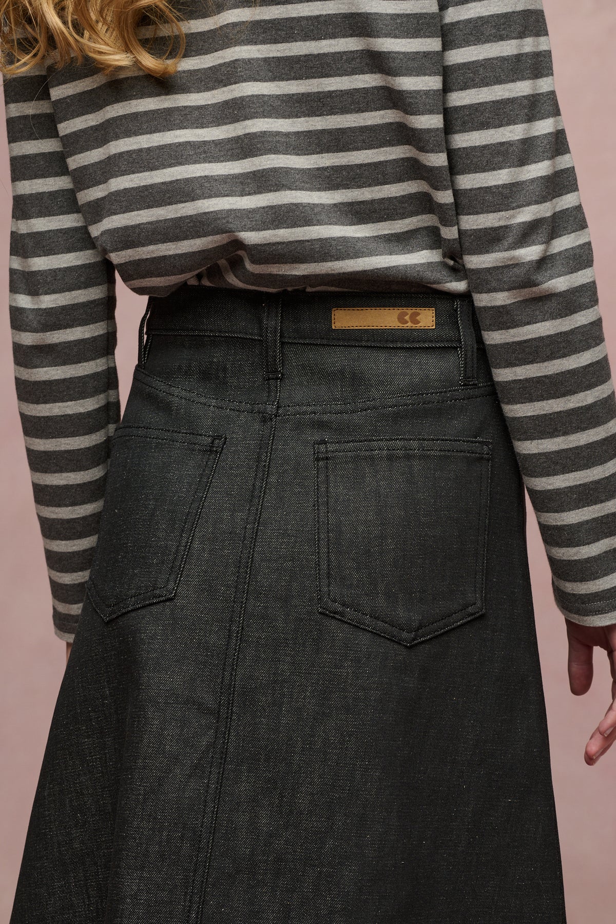 Close up of the back of Bobbie a line denim skirt in black, two back pockets, jean CC logo patch and belt loops