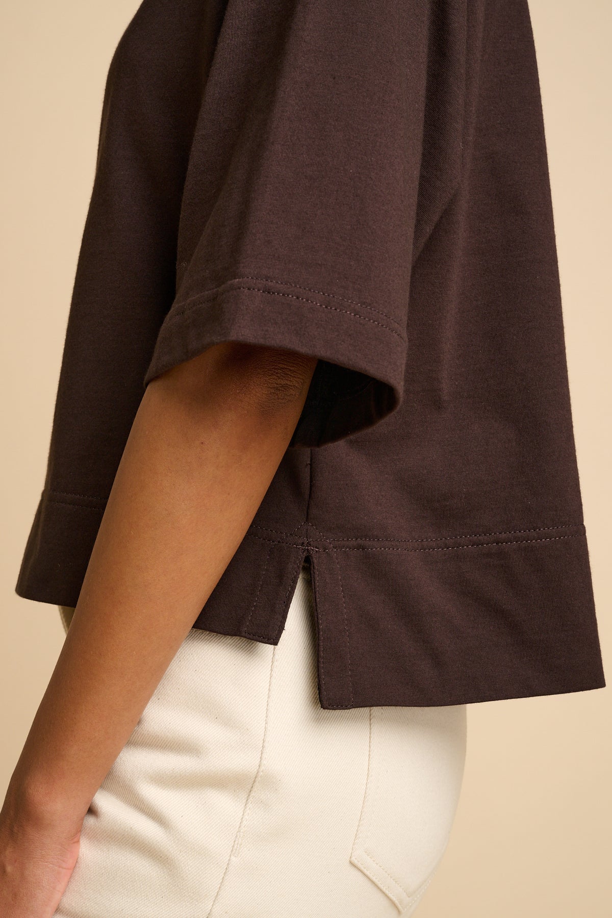 Brown t-shirt worn by a person on a beige background