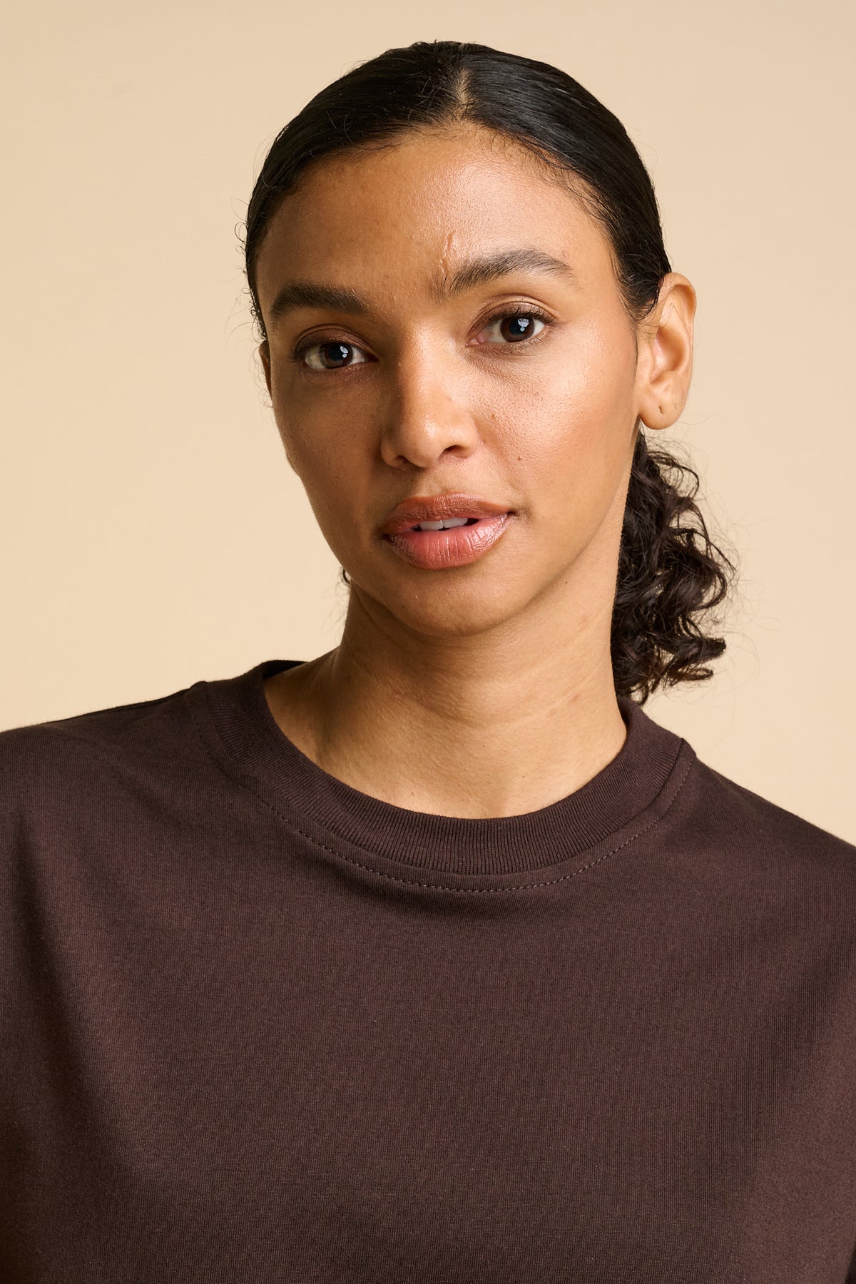Woman wearing a brown shirt against a beige background