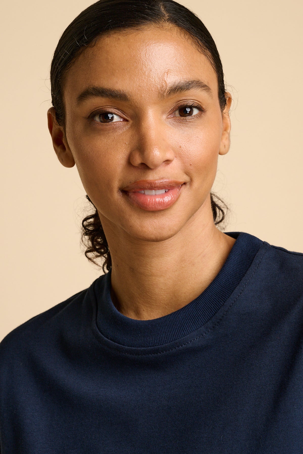 Woman wearing a navy blue t-shirt against a beige background