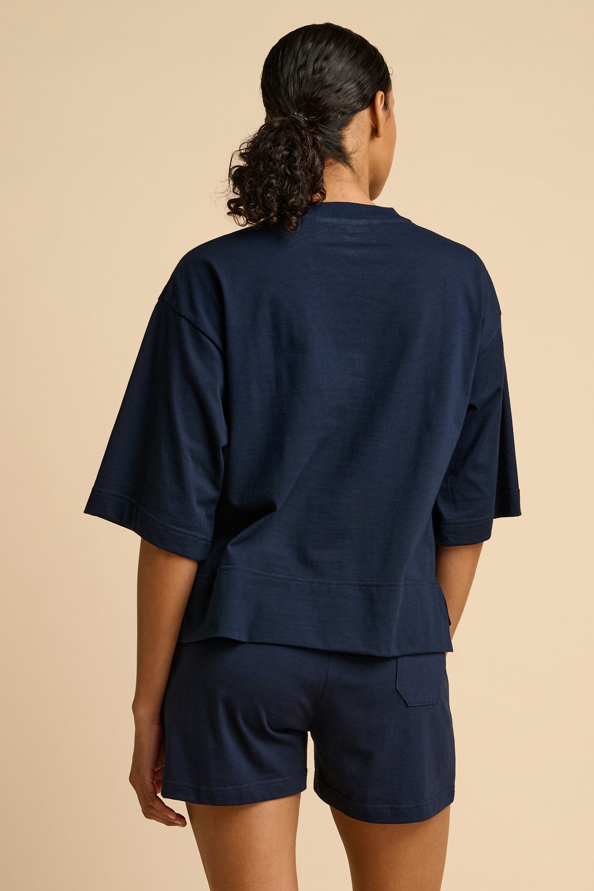 Person wearing a navy blue outfit on a beige background