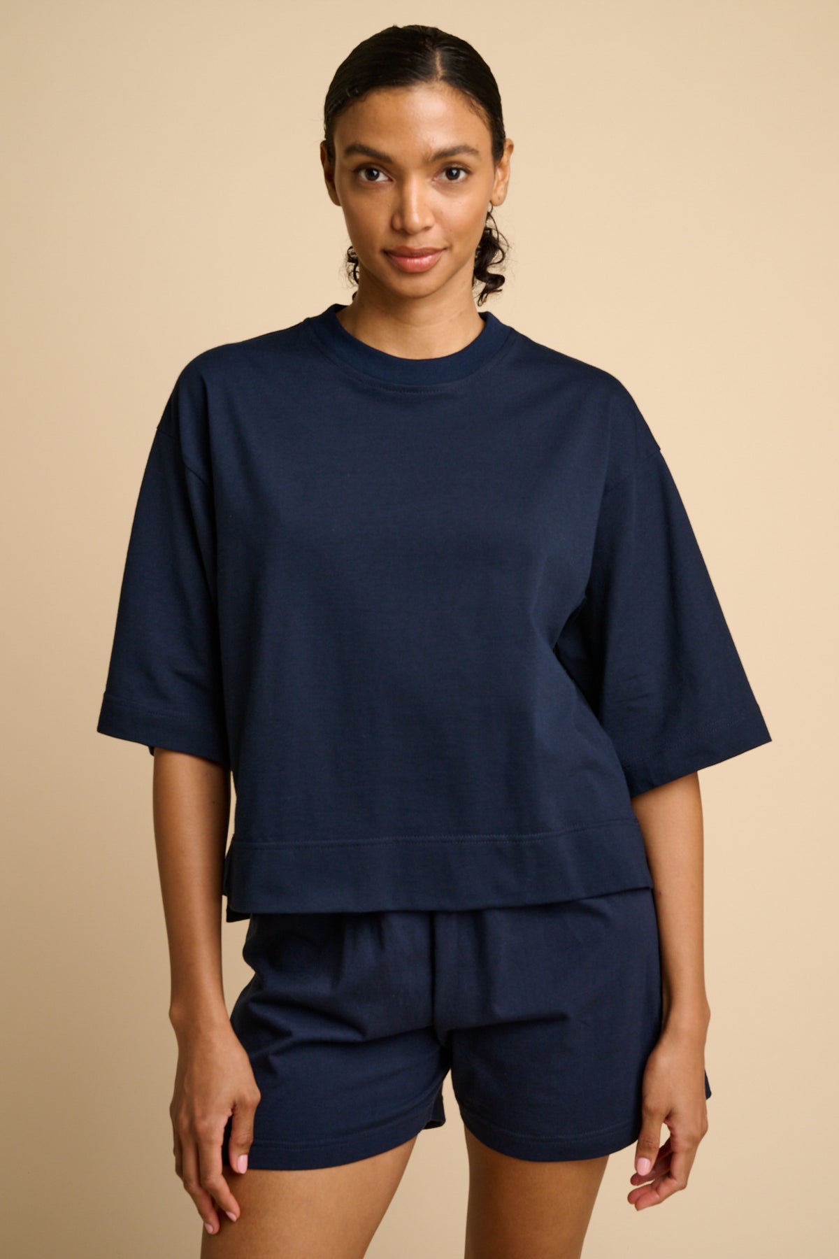 Woman wearing a navy blue outfit on a beige background