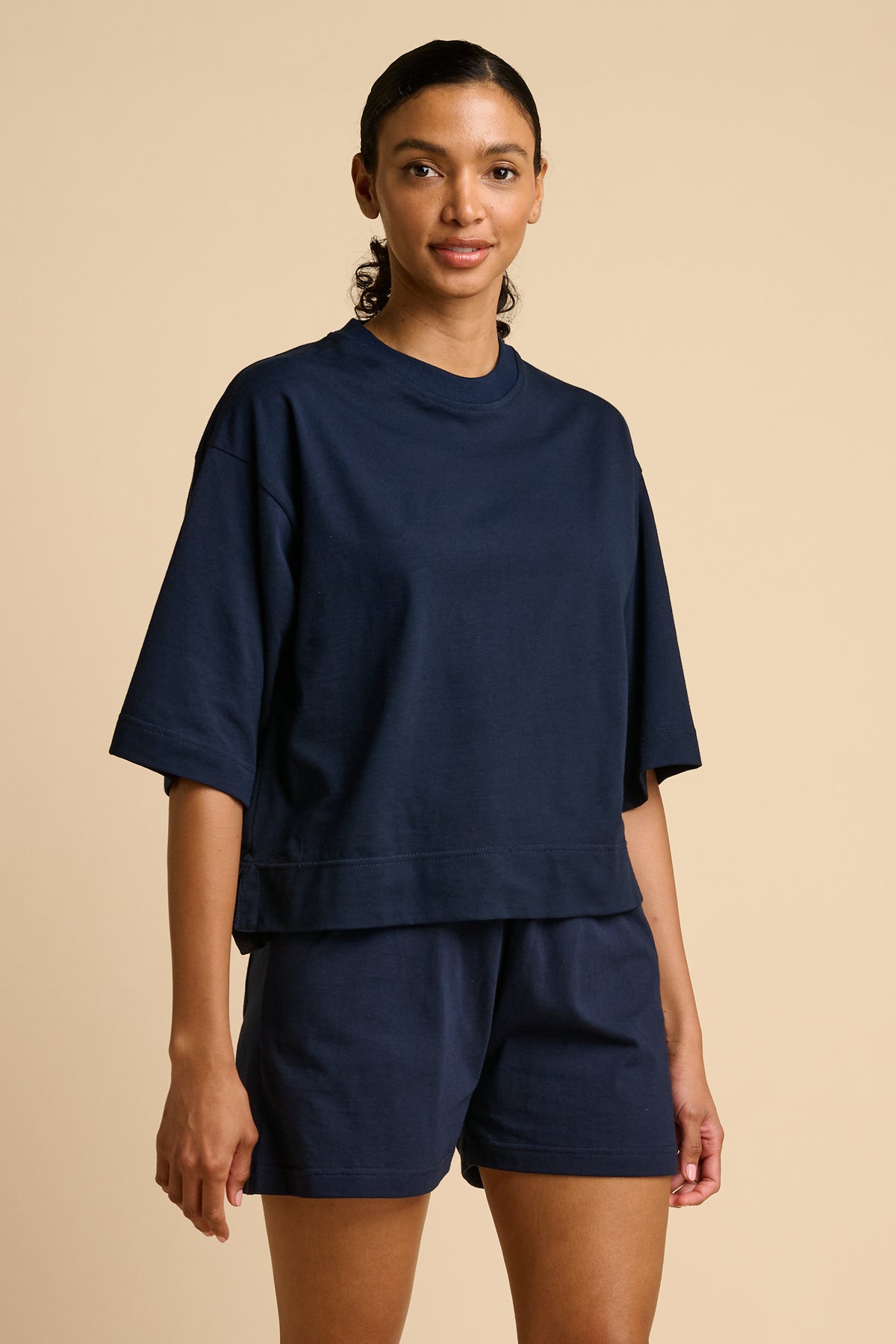 Woman wearing a navy blue outfit on a beige background