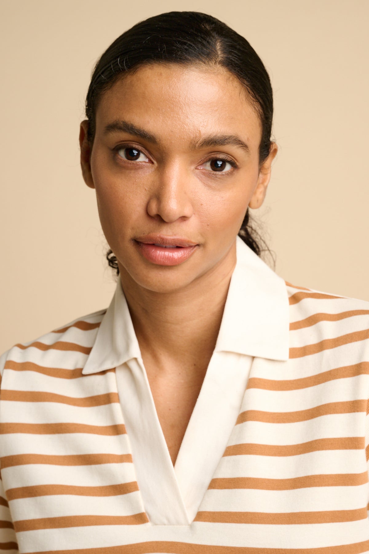 Woman wearing a striped shirt against a beige background