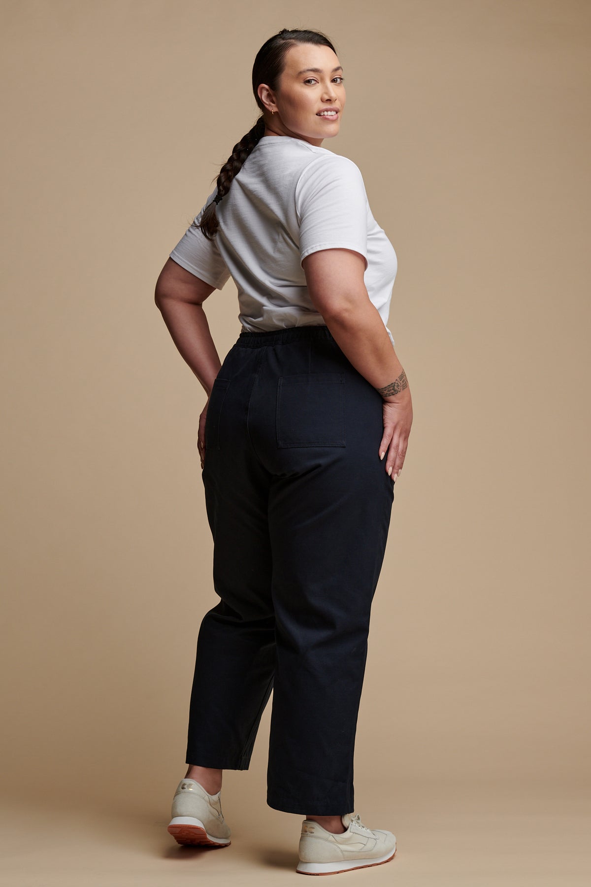 The back of female wearing camerawoman drawstring tapered cotton canvas trousers in navy paired with v neck T shirt in white.