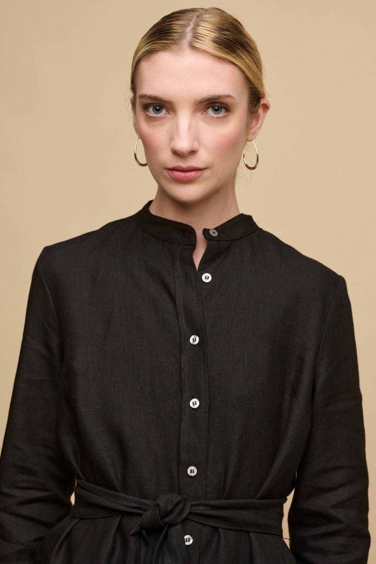 Waist up image of female wearing collarless shirt dress in black linen