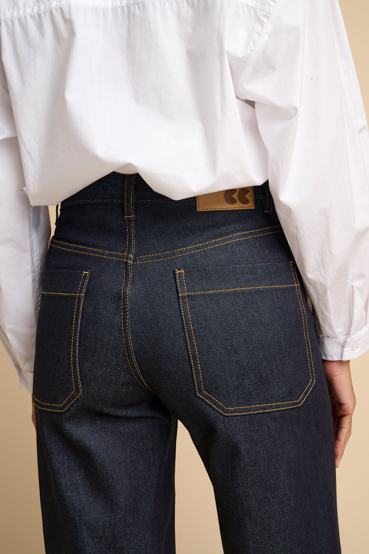 Person wearing indigo jeans with a beige background