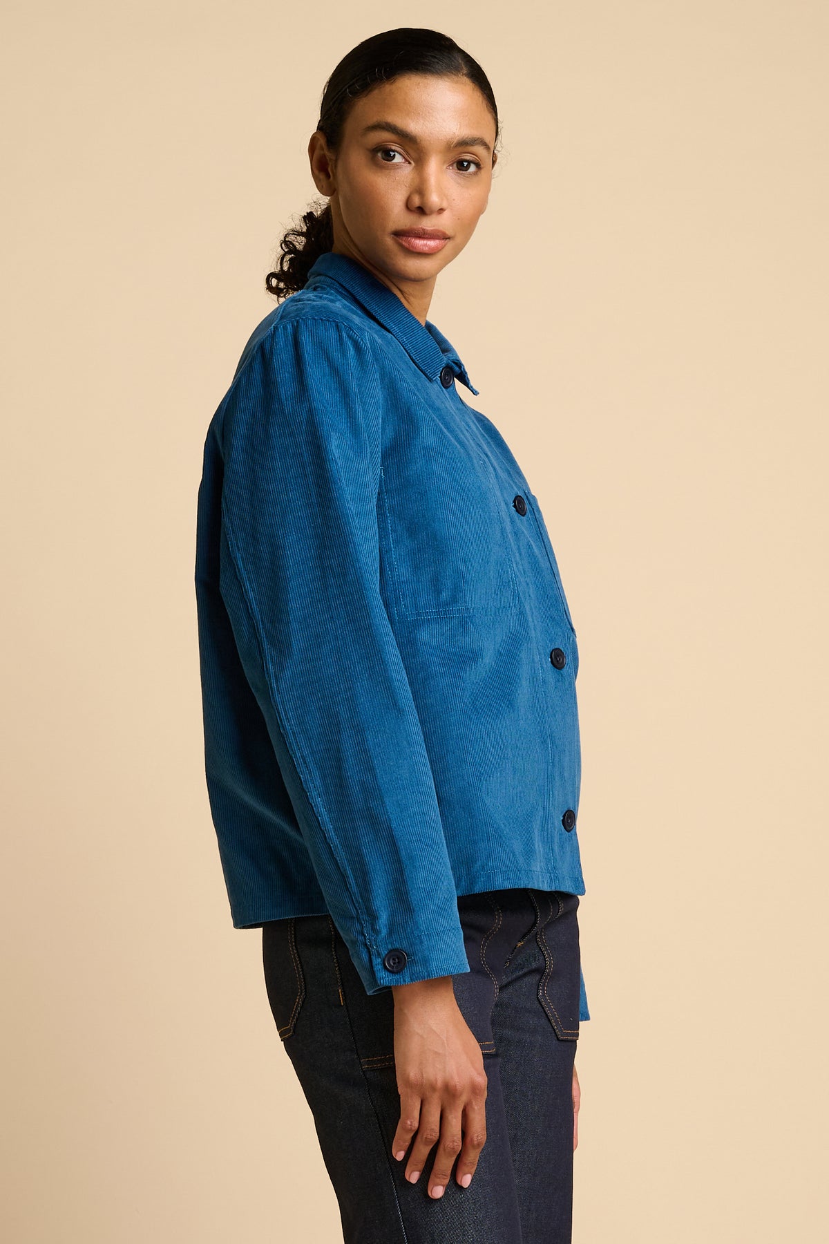 Woman wearing a blue jacket against a beige background
