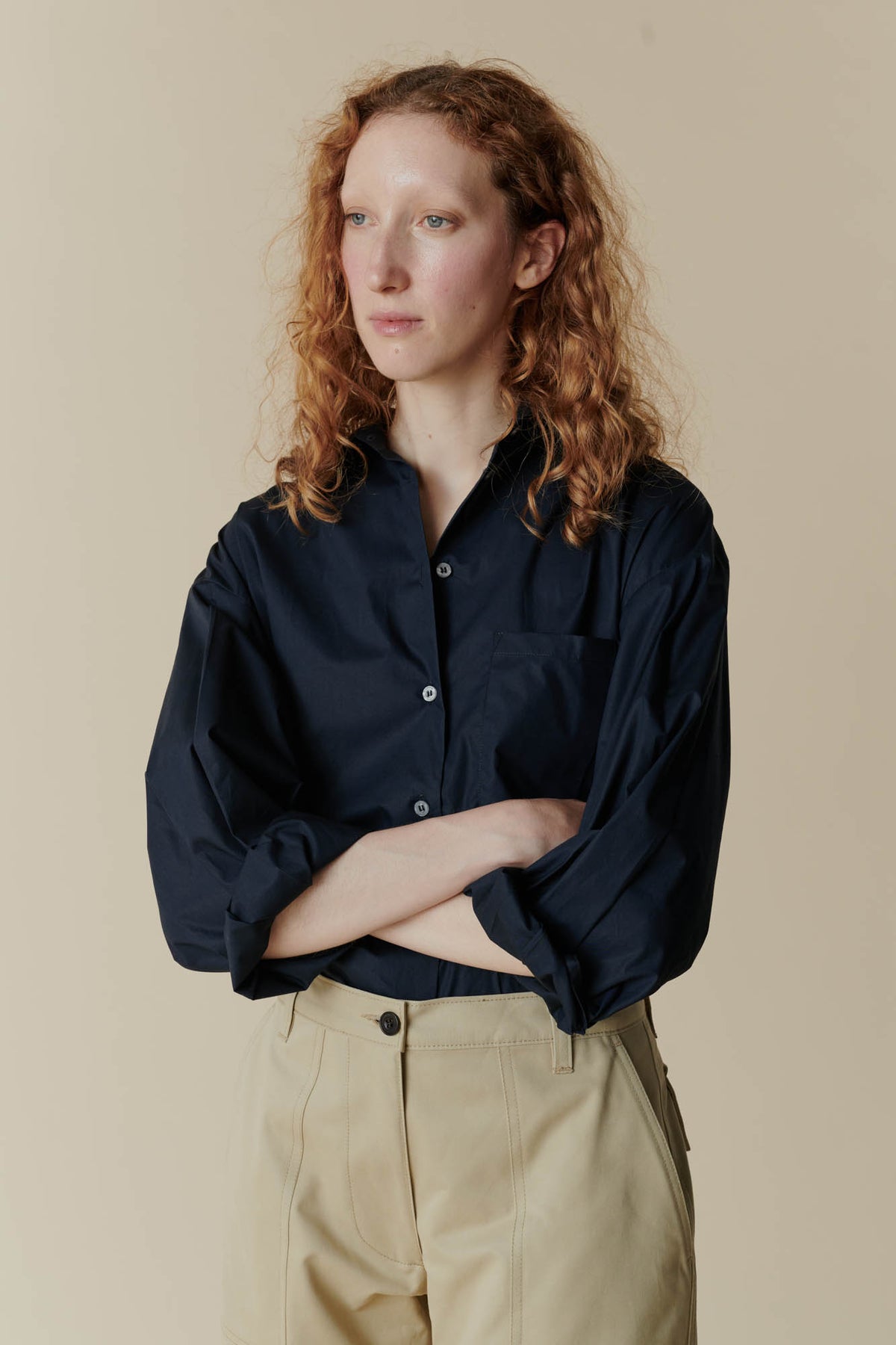 female wearing the navy long sleeve shirt with the combat pant in front of an beige background