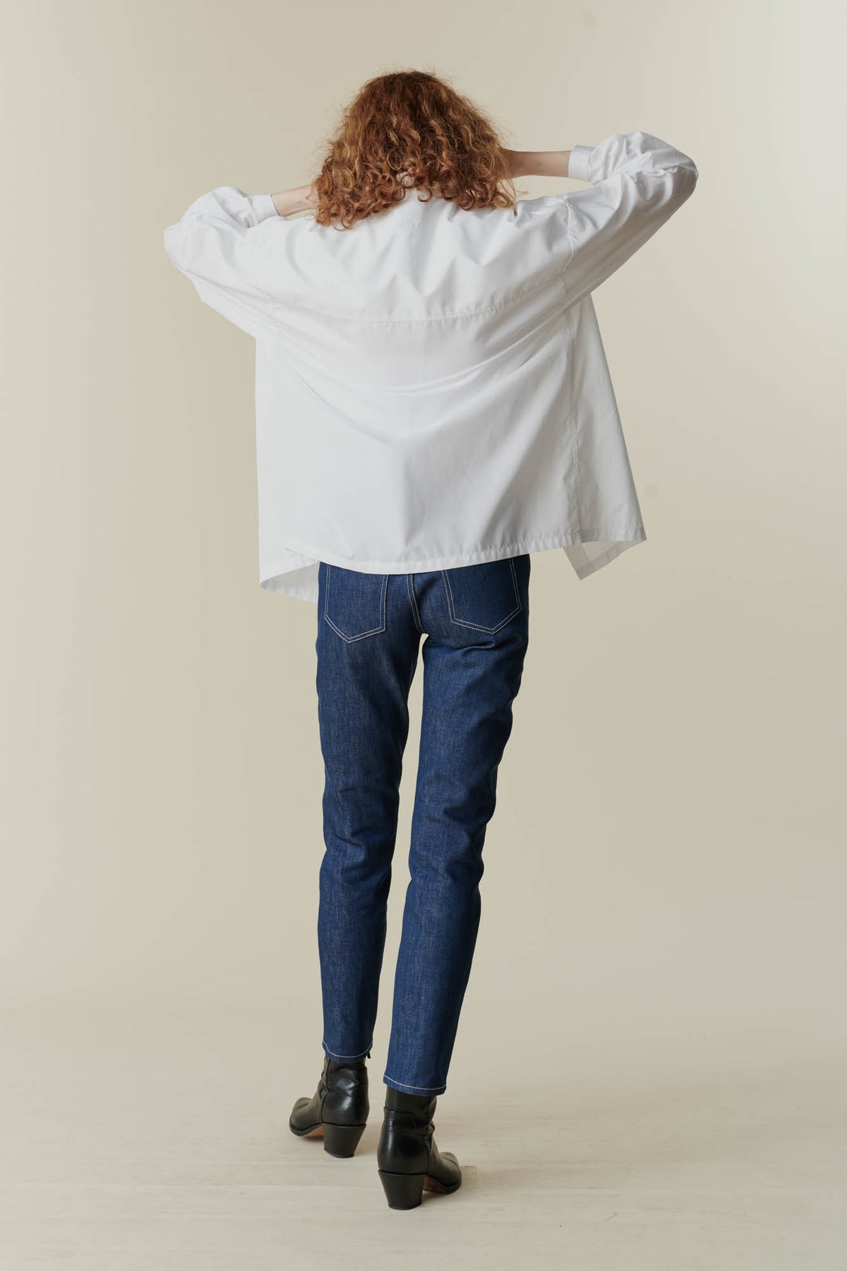 behind image of woman wearing esme long sleeve white shirt and some blue community clothing jeans