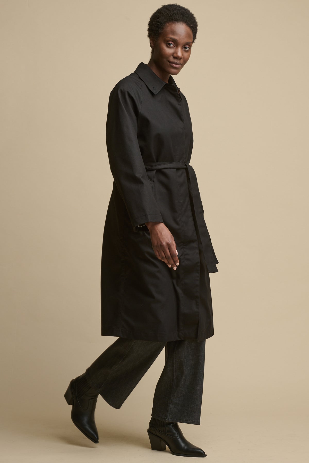 Full body image of female wearing women's Frances Raglan Belted Raincoat in black