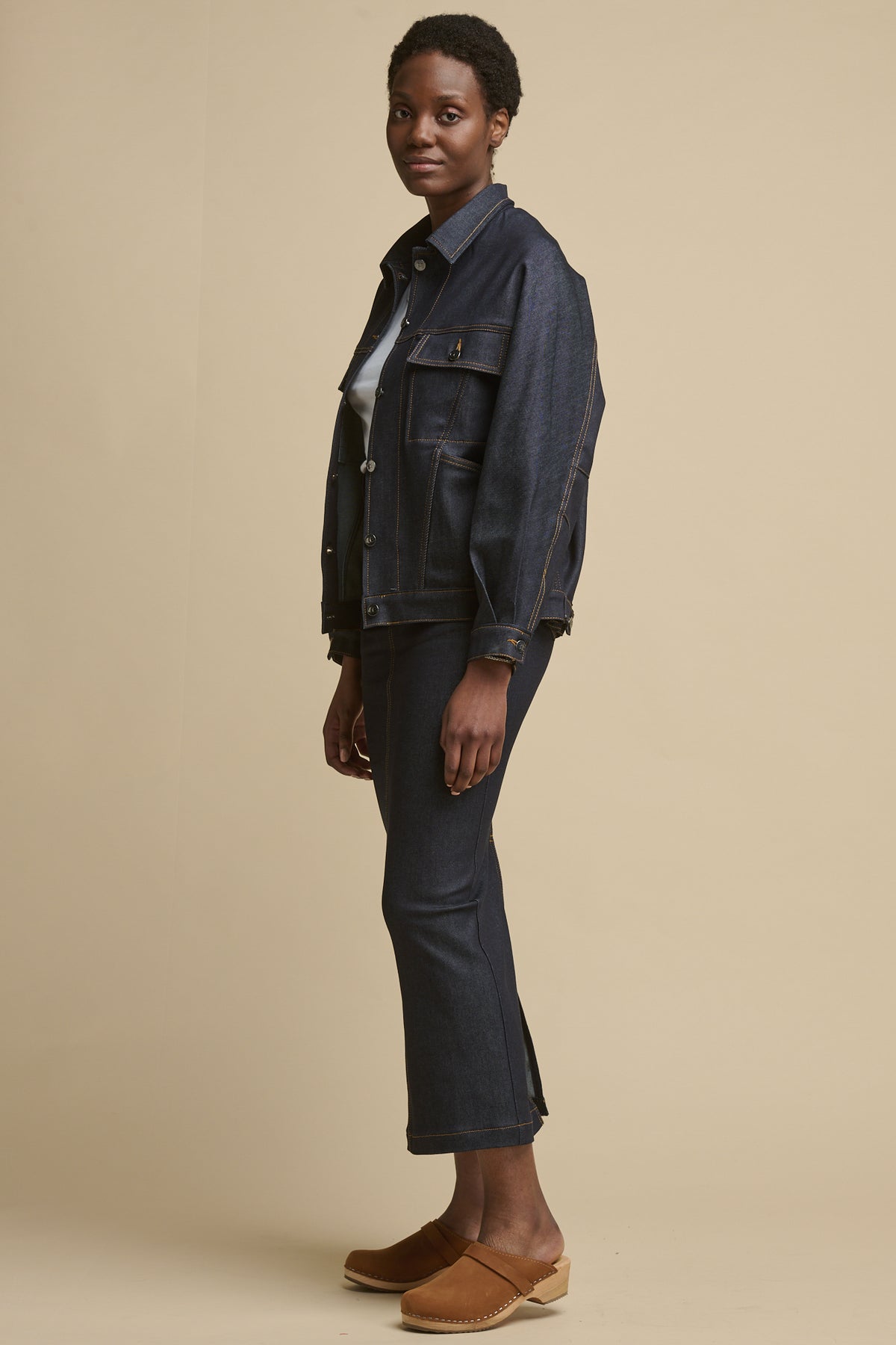 full body image of the side of female wearing Frankie denim maxi skirt with split hem paired with matching indigo denim Jodie jacket