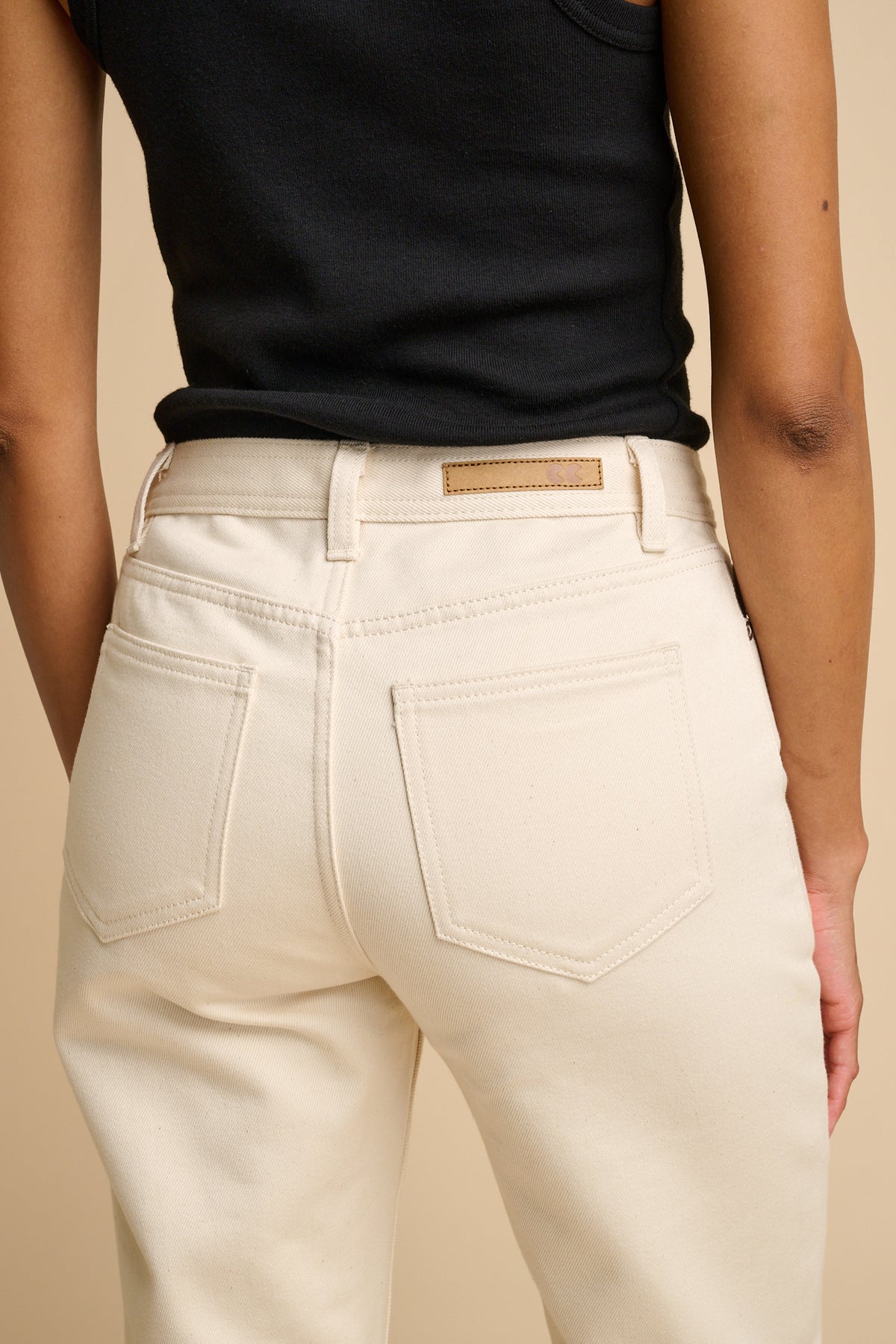 Female wearing ecru jeans on a beige background