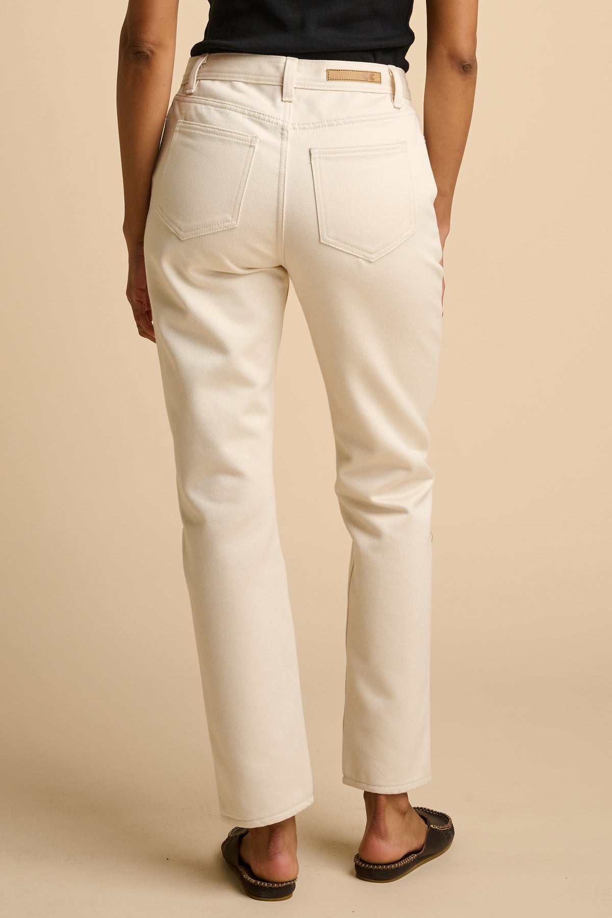 Female wearing ecru jeans on a beige background