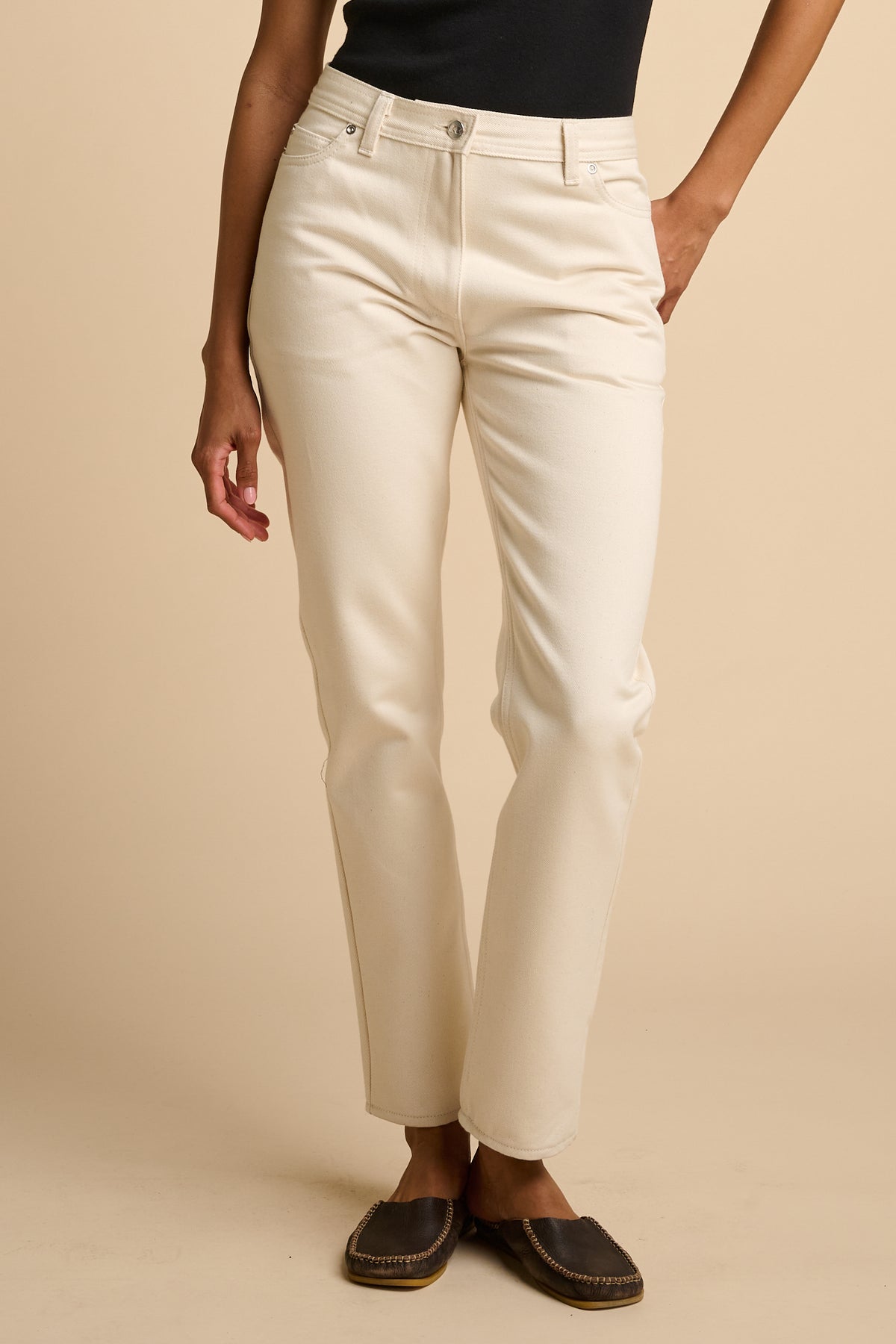 Female wearing ecru jeans on a beige background