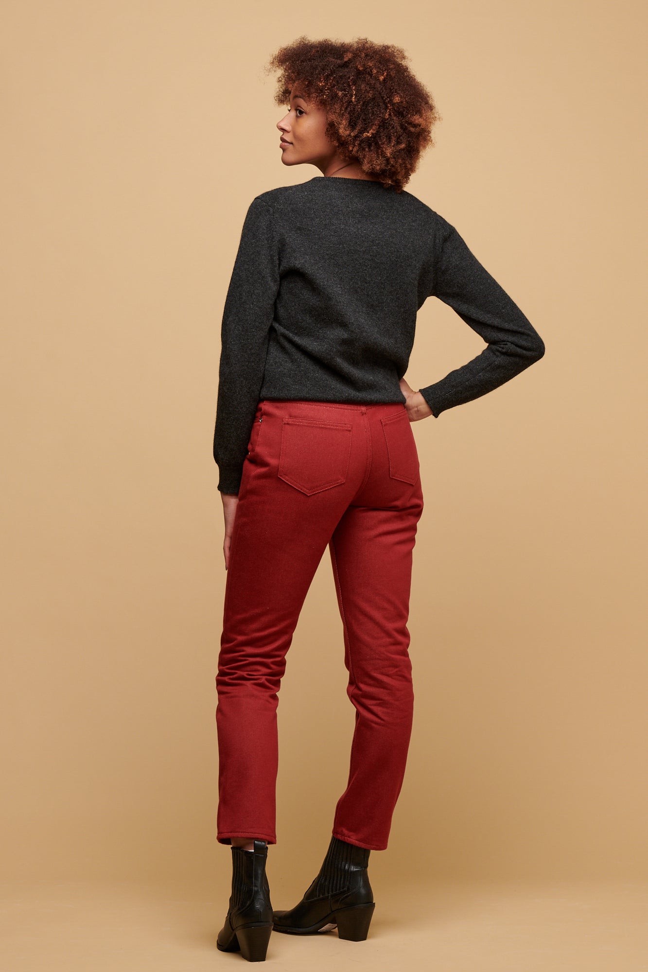 The front of female of colour wearing Gloria jean in burgundy paired with lambswool crew neck in charcoal with Jodie denim jacket over the top and a black boot.
