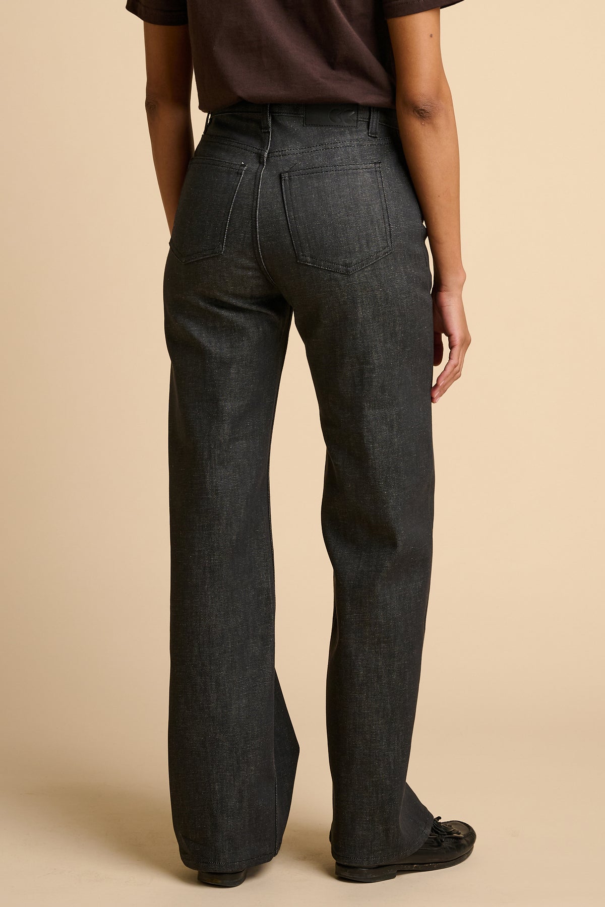 Woman wearing black jeans on a beige background