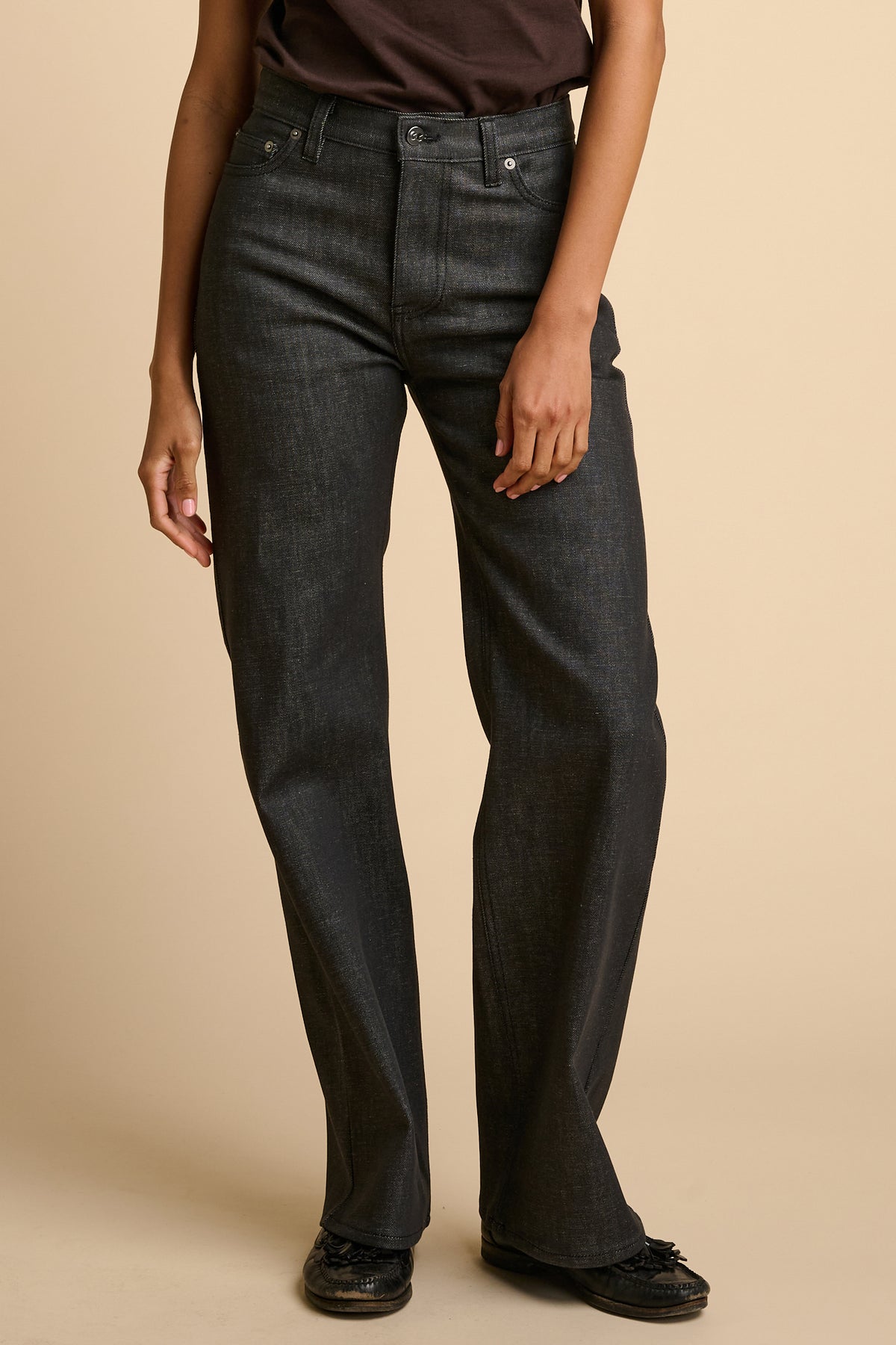Person wearing black jeans on a beige background