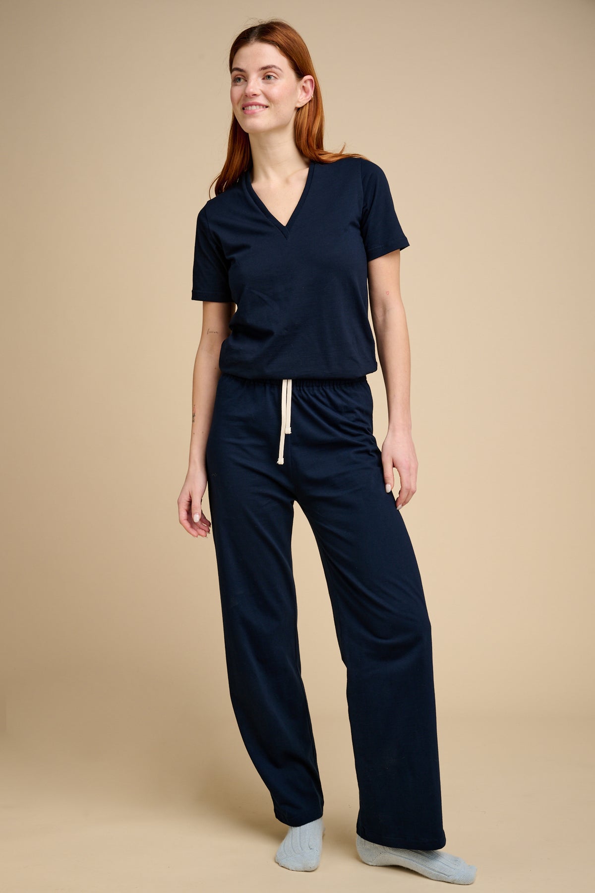 Woman wearing navy pyjama bottoms with matching navy v neck t shirt