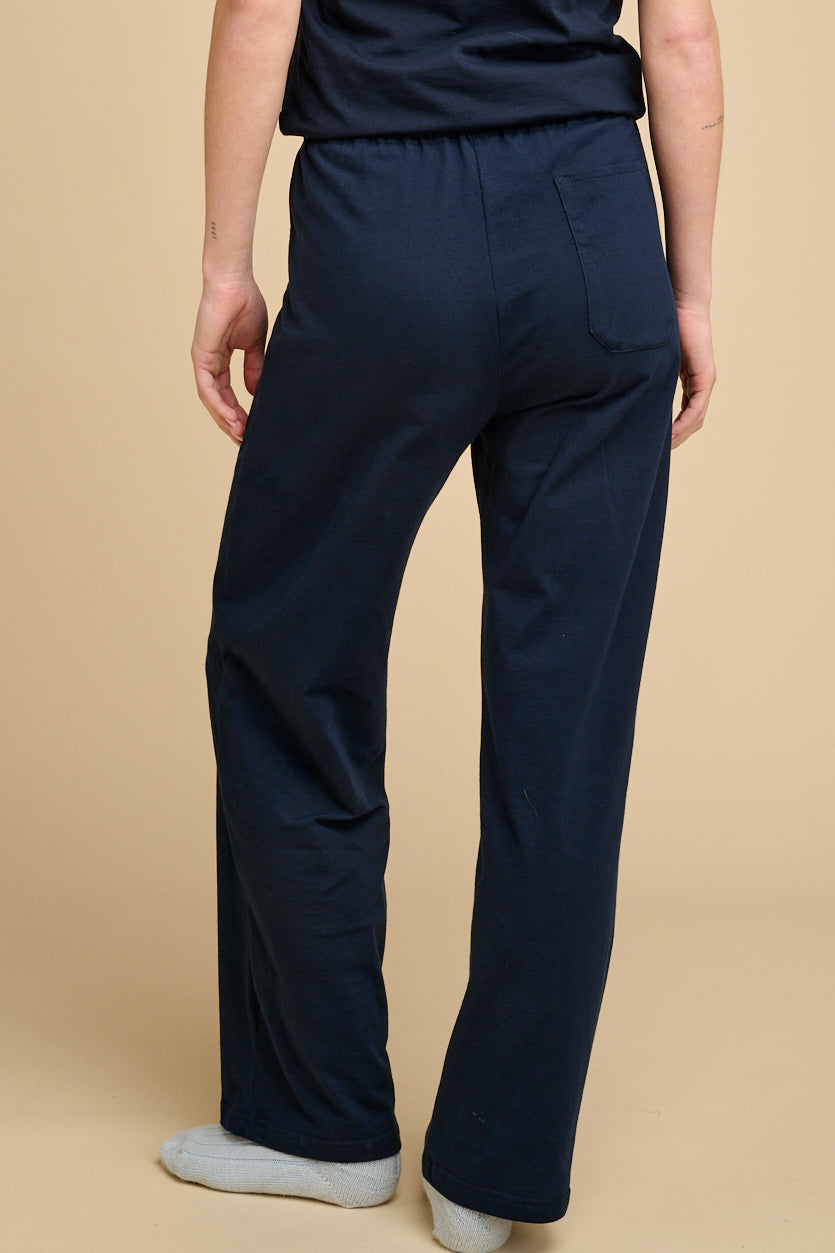 The back of woman waist down wearing navy pyjama bottoms with matching navy t shirt