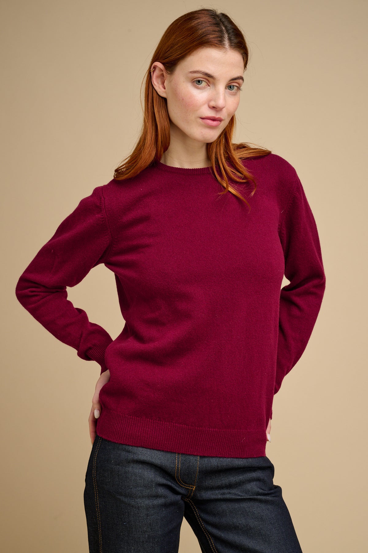 Woman wearing a burgundy sweater against a beige background