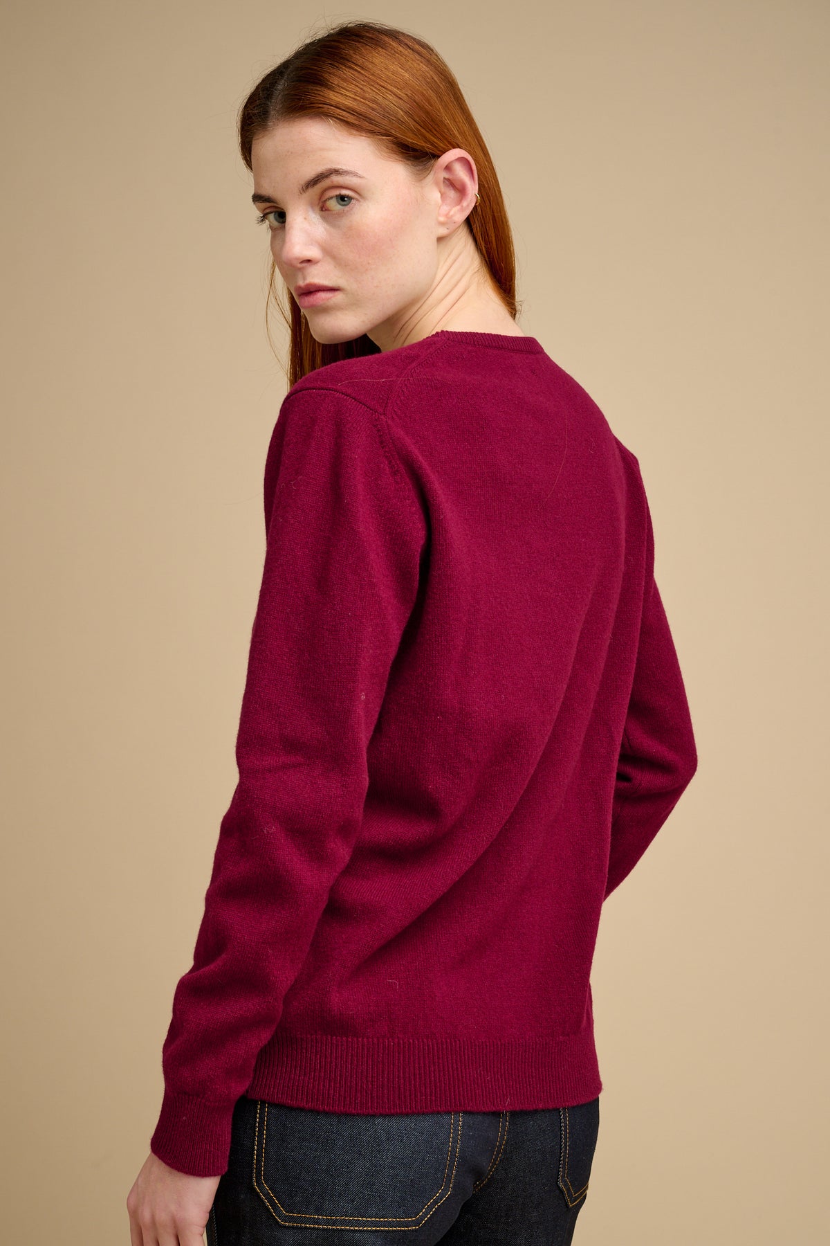 Woman wearing a burgundy sweater against a beige background