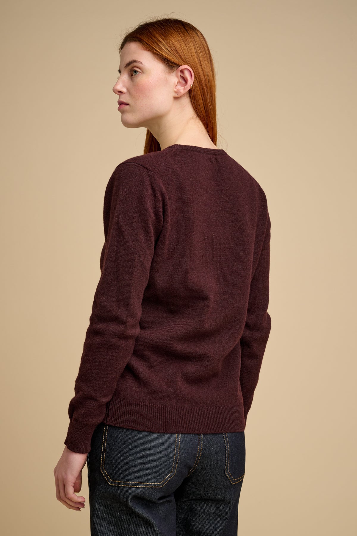 The back of woman wearing lambswool crew neck jumper in chocolate.