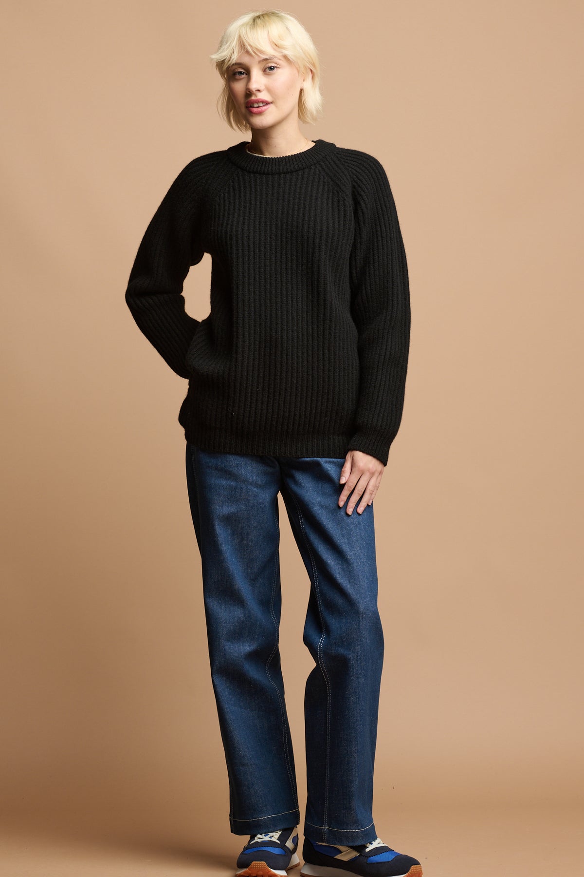 female with blonde hair wearing lambswool fisherman ribbed jumper in black paired with women's work jeans in blue