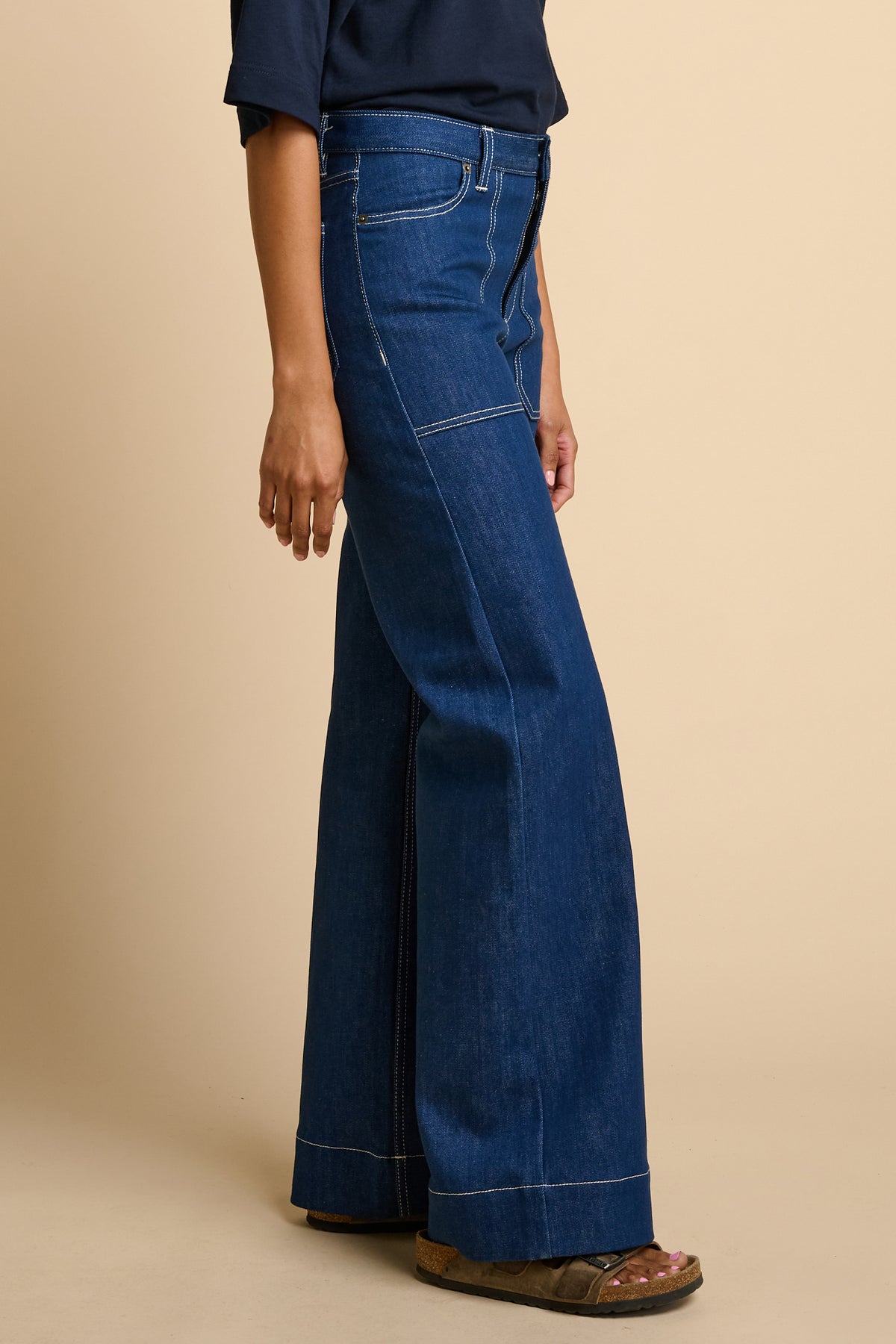 Woman wearing blue jeans on a beige background