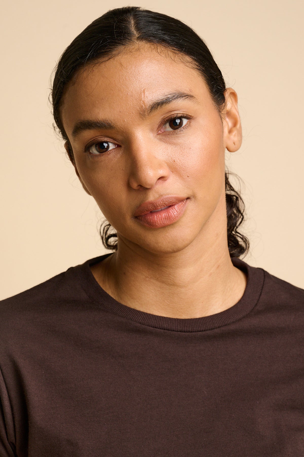 Woman wearing a brown shirt against a beige background