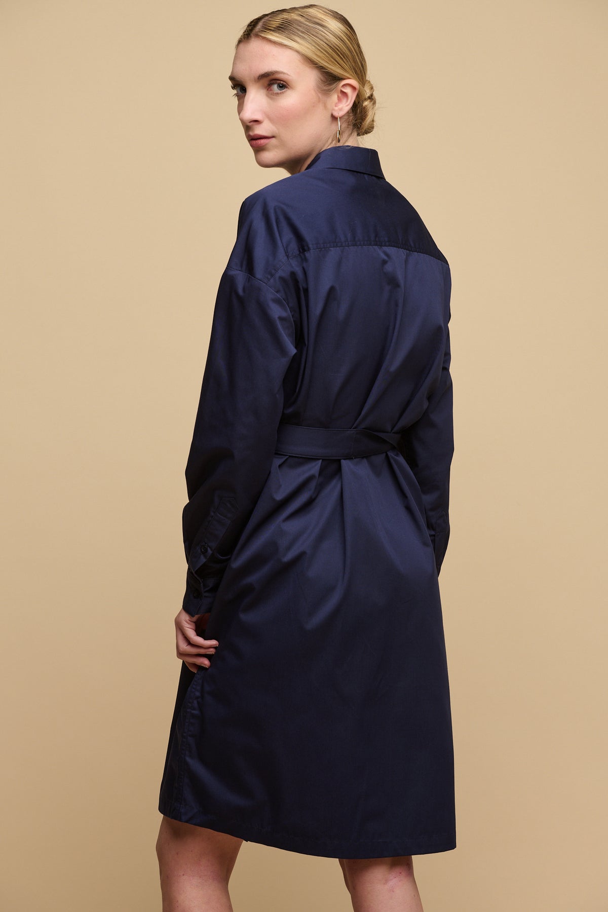 Thigh up image of the back of blonde female with hair tied up wearing Lorelle belted midi cotton shirt dress in navy