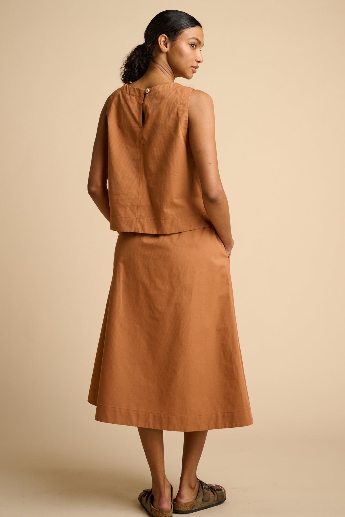 Woman wearing cinnamon top and skirt. 