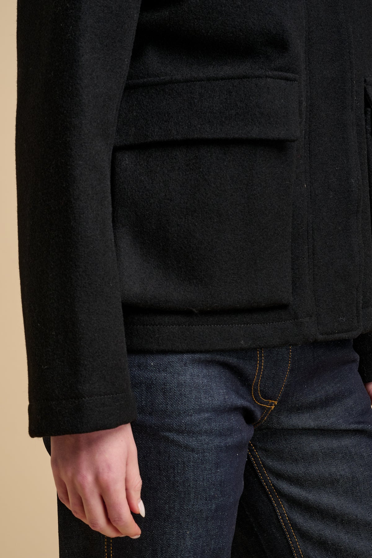 Close up of wool jacket in black with big front pockets with flaps.