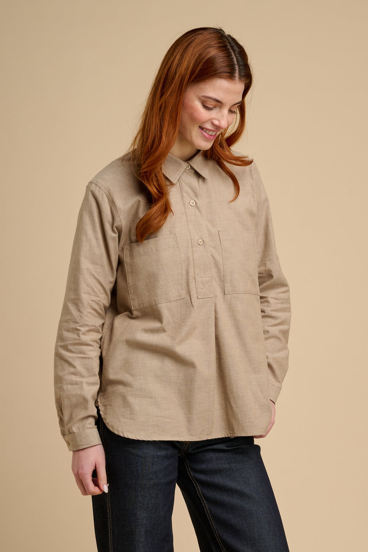 Woman wearing a beige shirt against a beige background.
