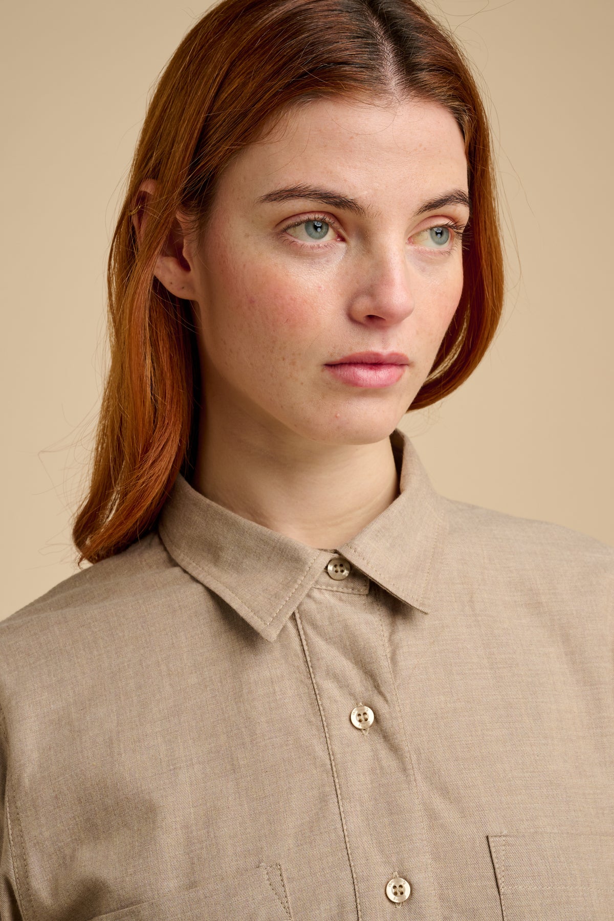 Woman wearing a beige shirt against a beige background