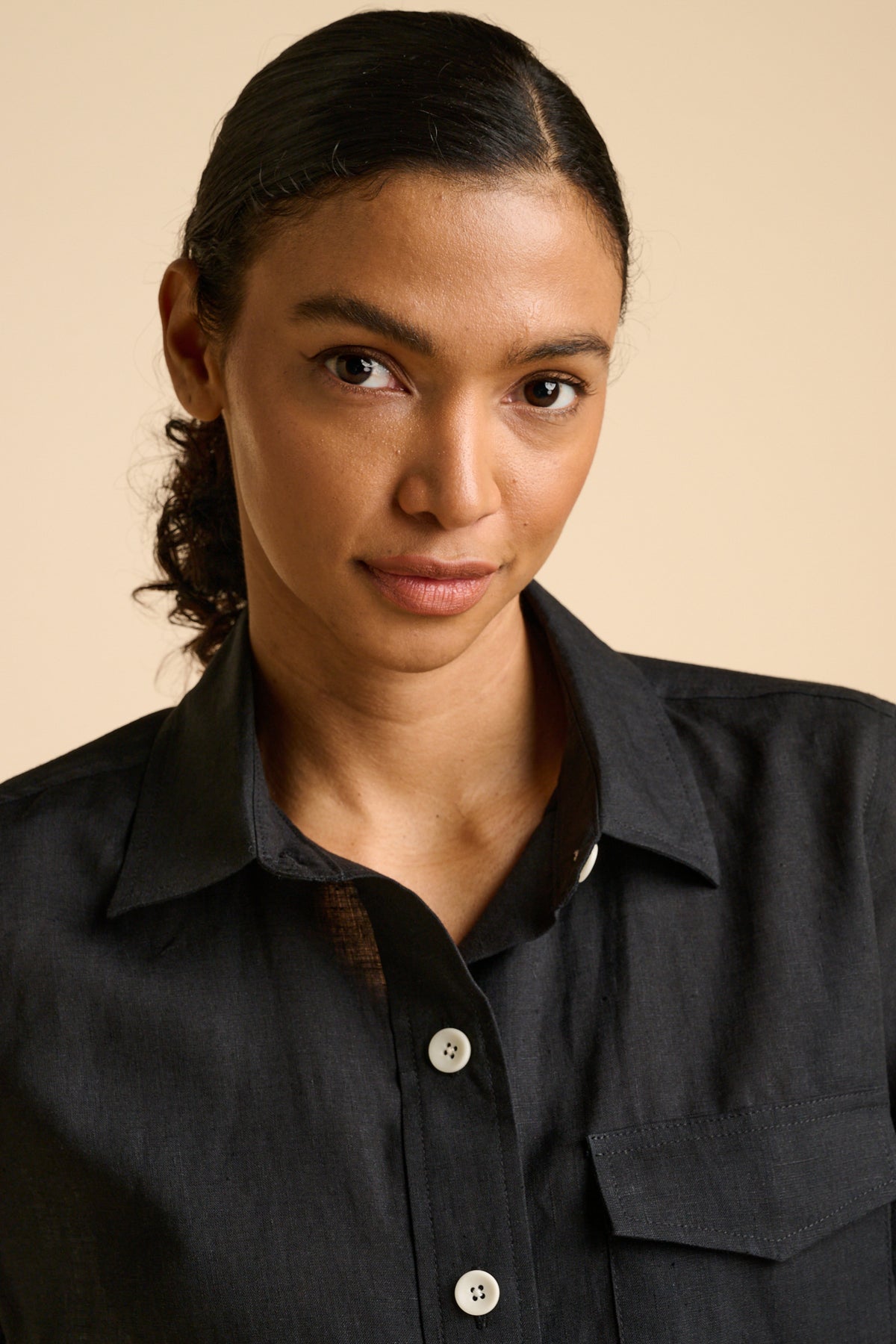 Woman wearing a black shirt against a beige background.