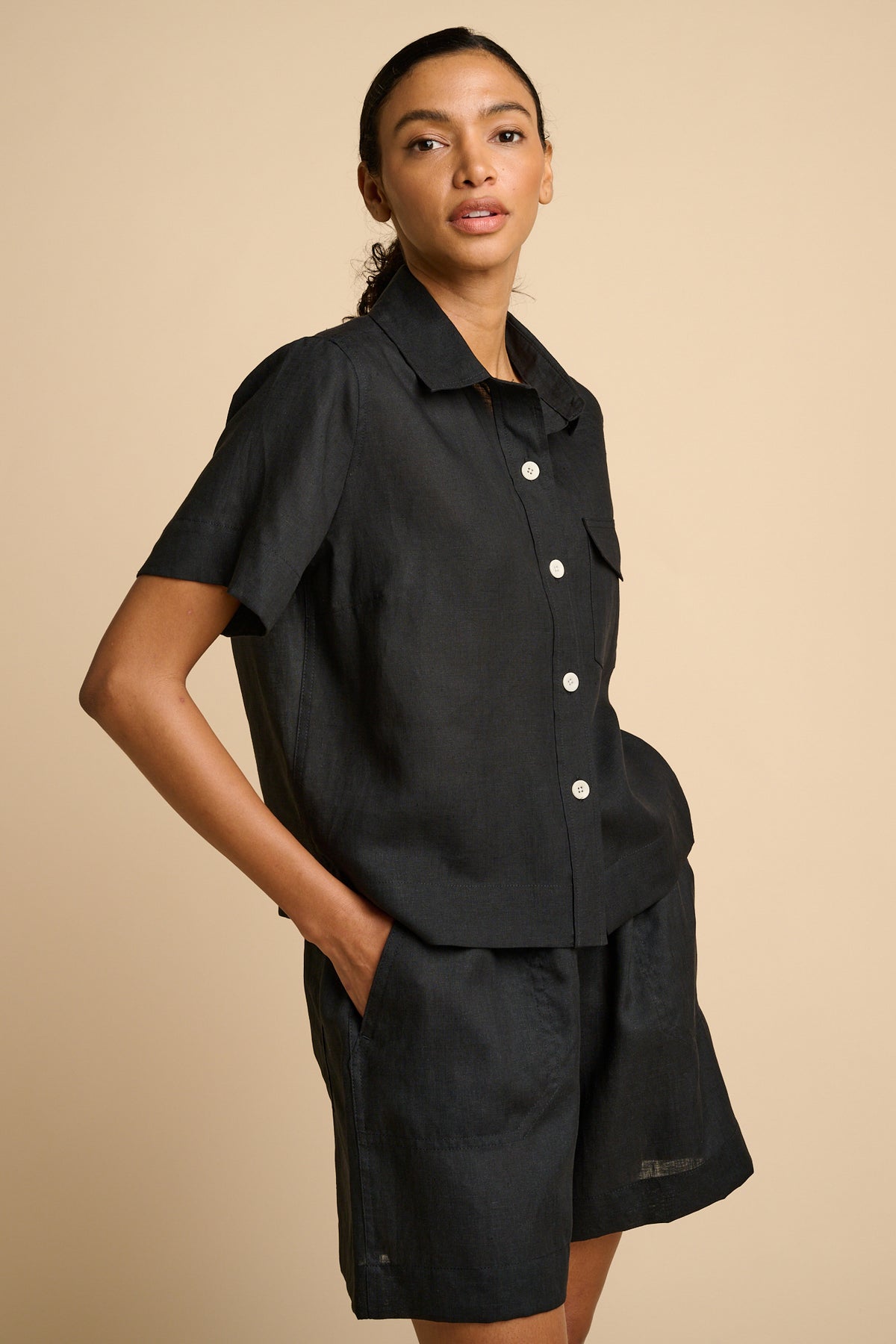 Woman wearing a black shirt and shorts on a beige background.