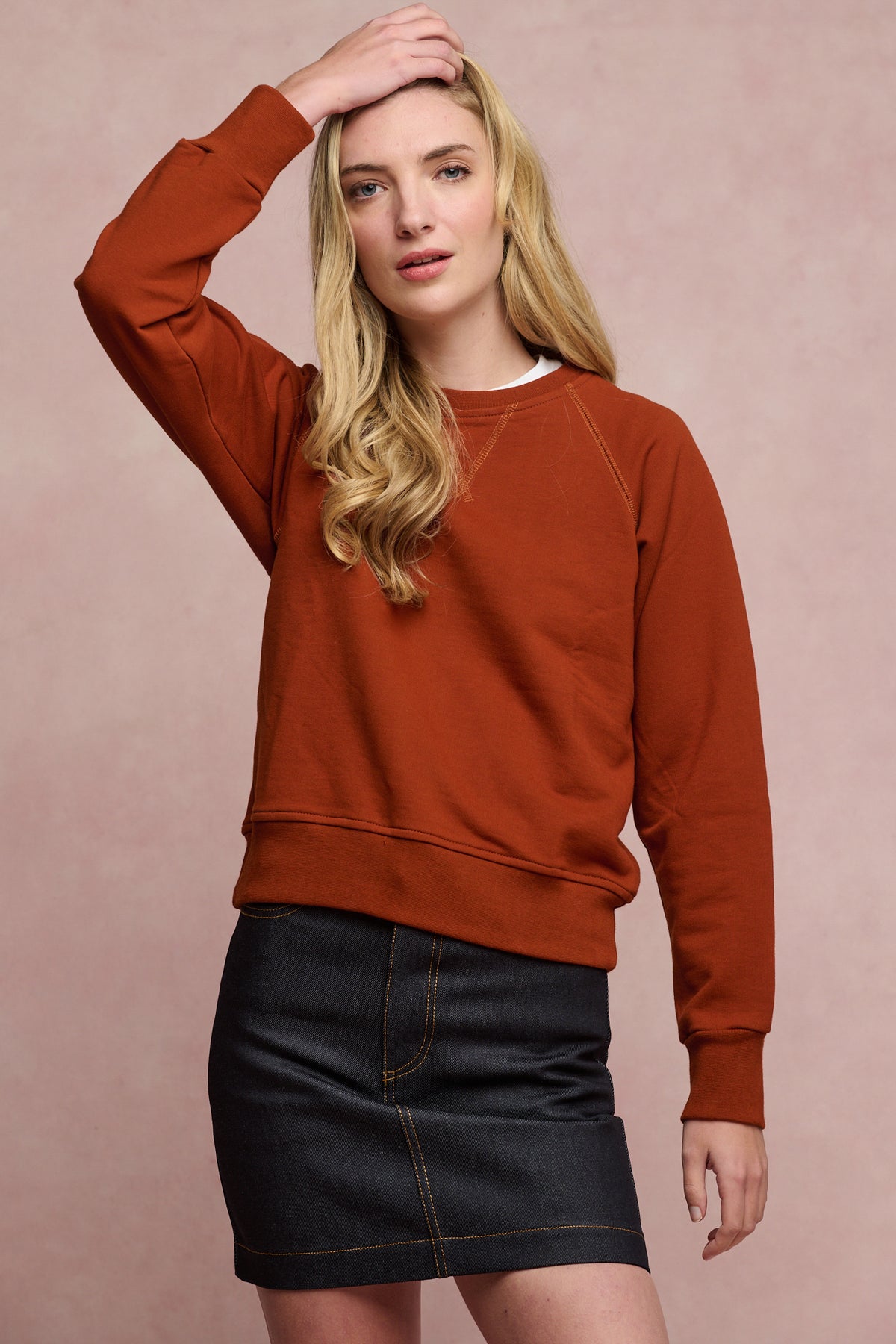 Thigh up image of female wearing raglan sweatshirt in cinnamon paired with charlie denim mini skirt in indigo