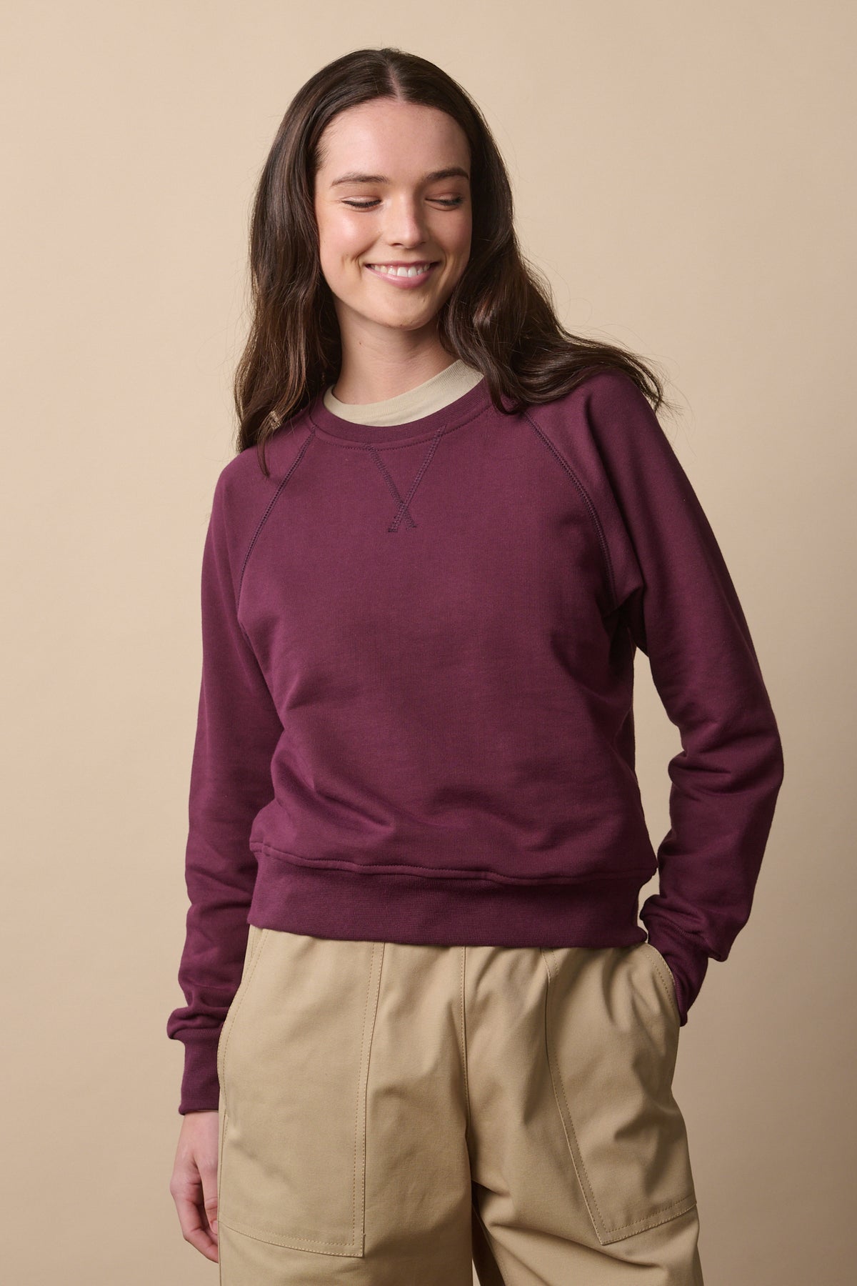 Thigh up of brunette female wearing raglan sweatshirt in plum 