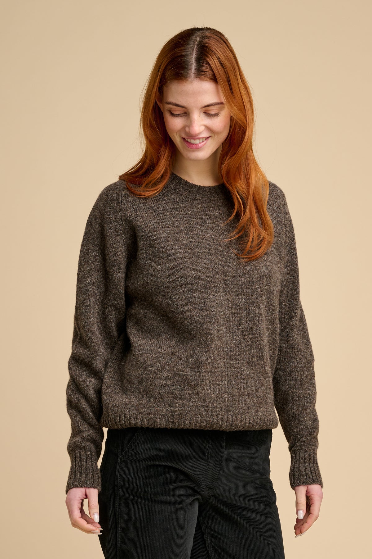 Woman wearing brown knit jumper against beige background