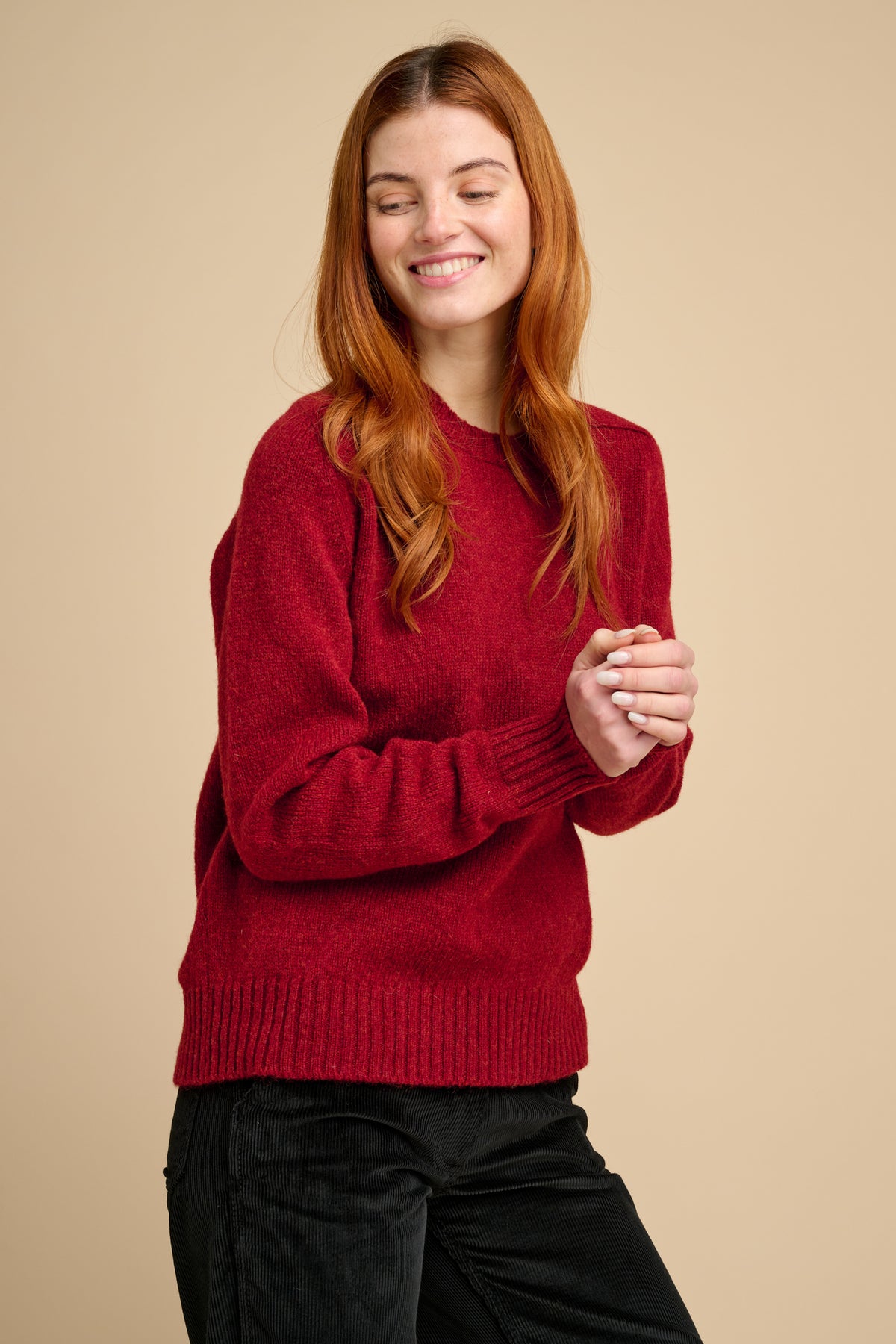 Woman wearing a red sweater against a beige background